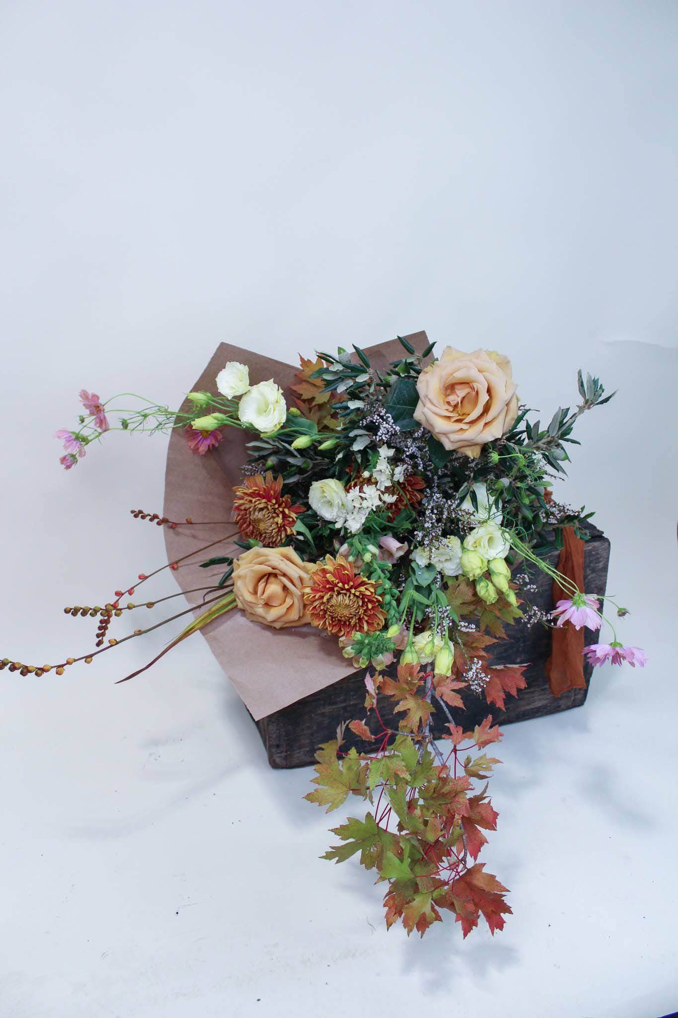 Bouquet of peach roses and mixed flowers in a rustic box