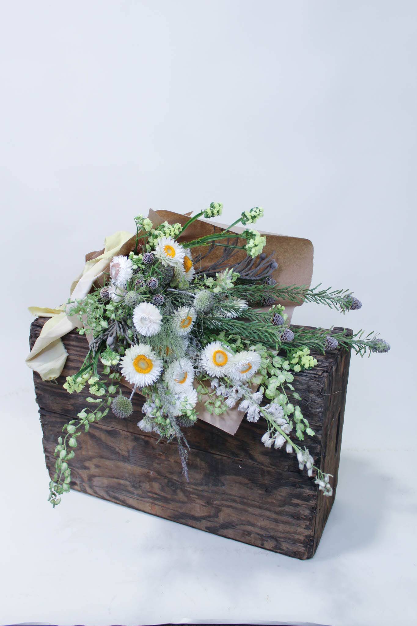 Rustic floral arrangement in a wooden box with white blooms and greenery