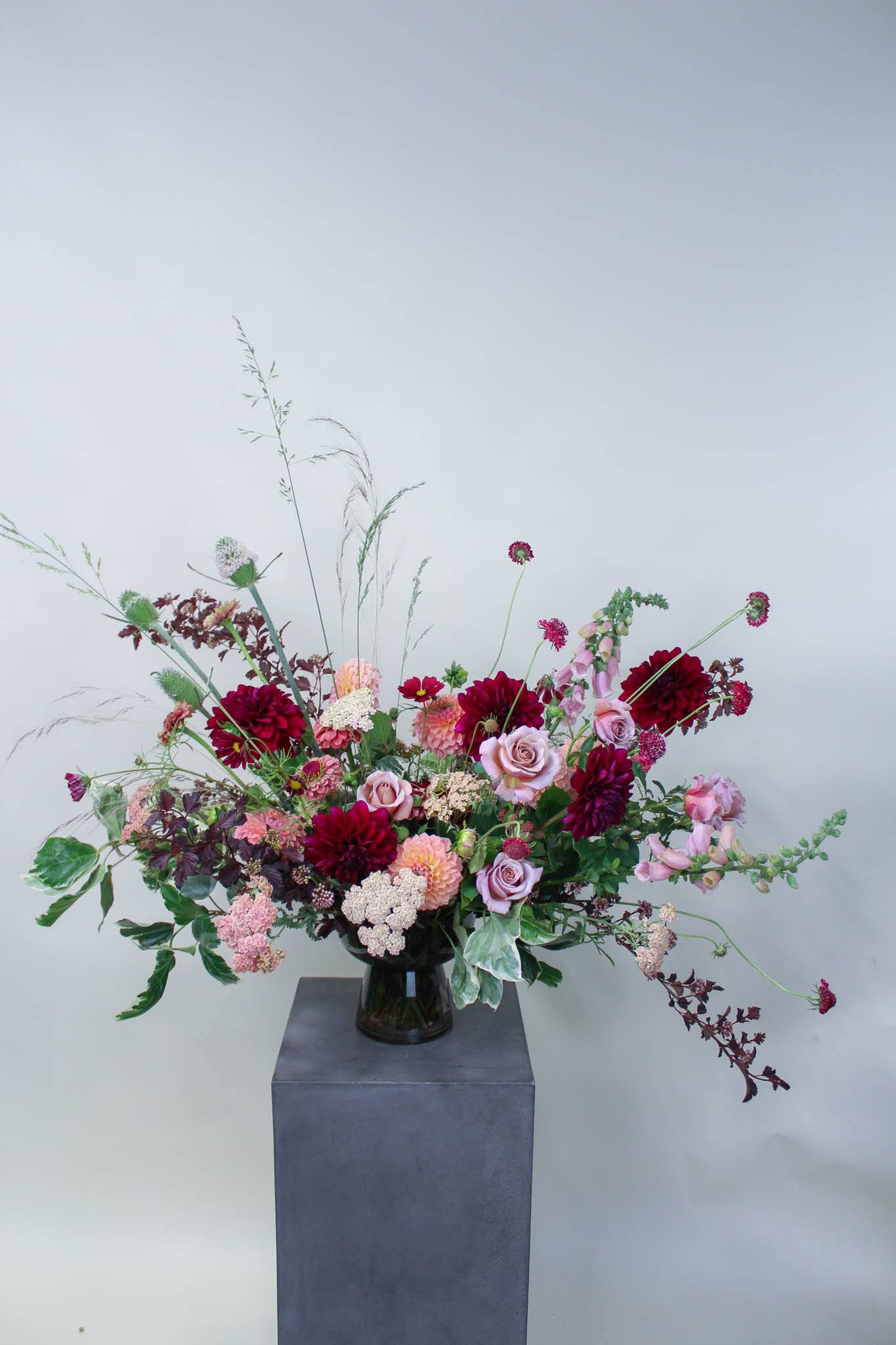 Large mixed bouquet of pink and burgundy flowers in a dark vase