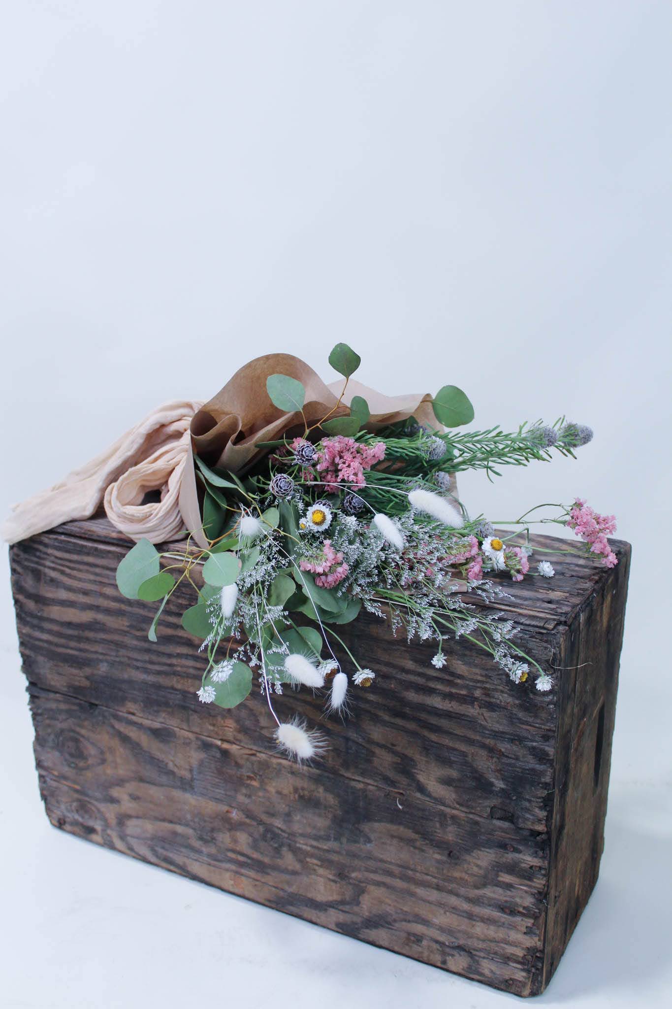 Wildflower bouquet in brown paper on a rustic wooden box