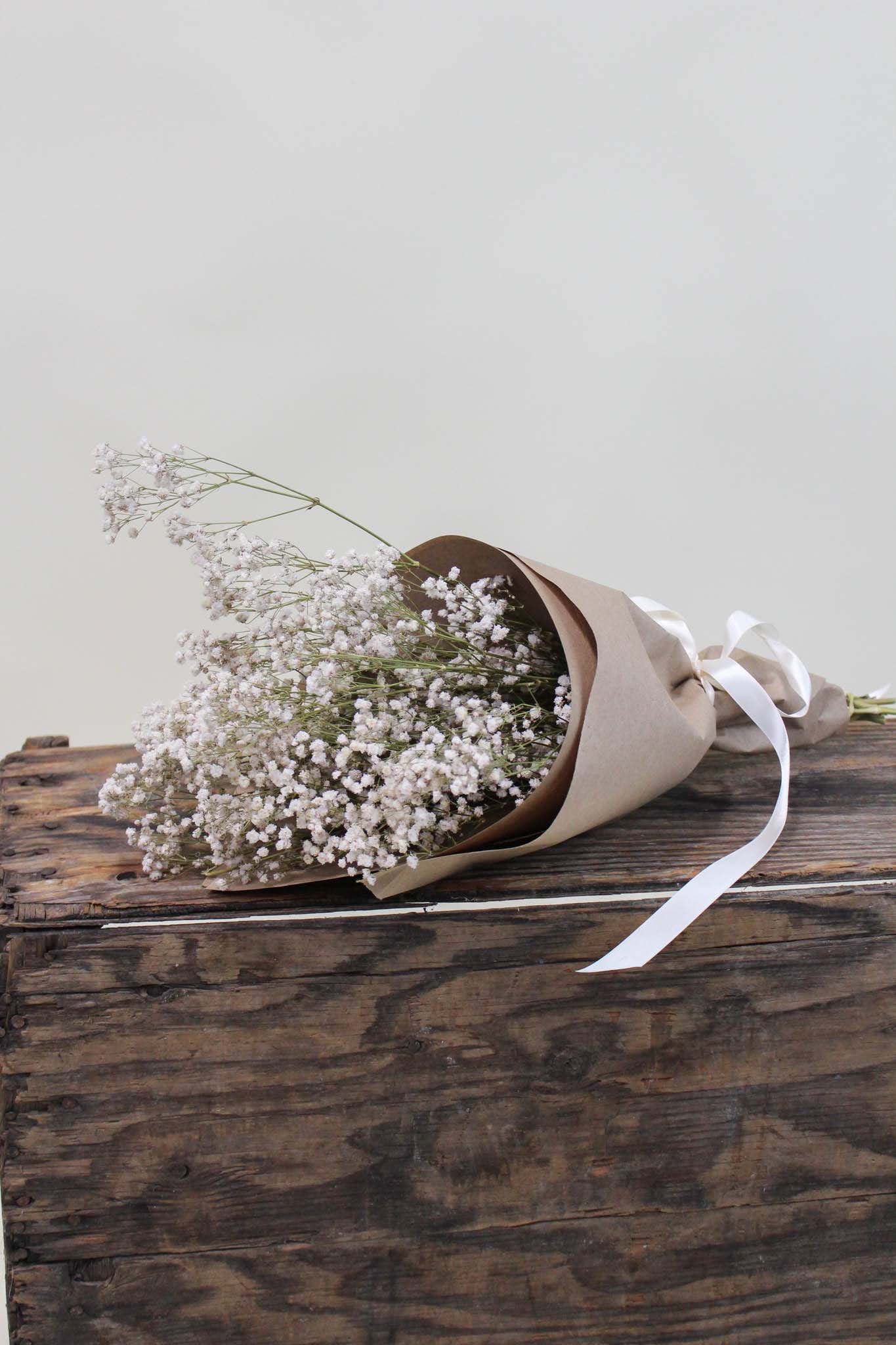 Bouquet of white baby's breath wrapped in brown paper with a white ribbon