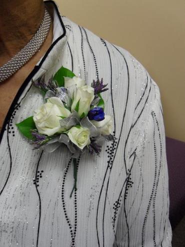 White and purple boutonniere pinned to a sequined jacket