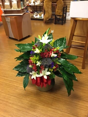 Mixed flower arrangement in a low container with white lilies and red blooms