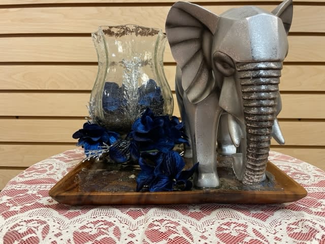 Silver elephant figurine beside a glass vase with dark blue flowers