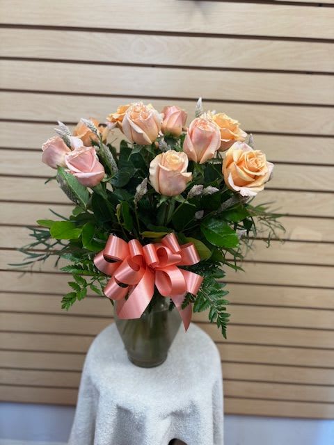 Pink and peach roses in a glass vase with a pink ribbon bow