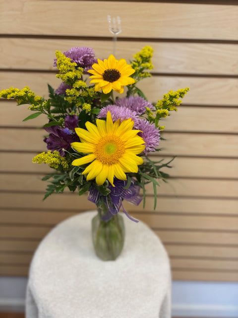 Bouquet of yellow sunflowers and purple flowers in a glass vase