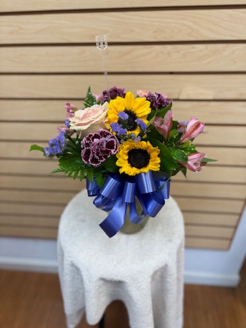 Mixed bouquet with sunflowers, roses, and alstroemeria tied with a blue ribbon