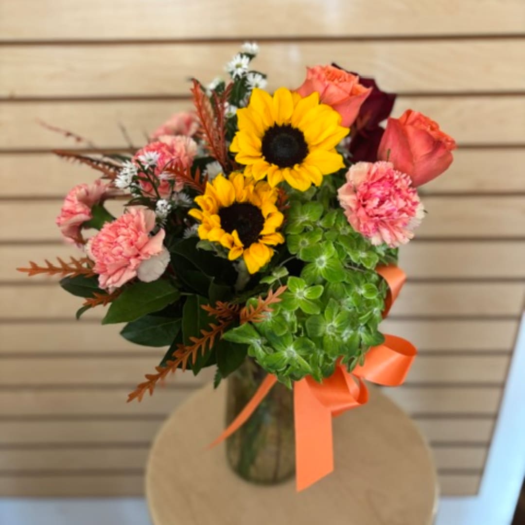 Bouquet with sunflowers, pink roses, and carnations in a vase