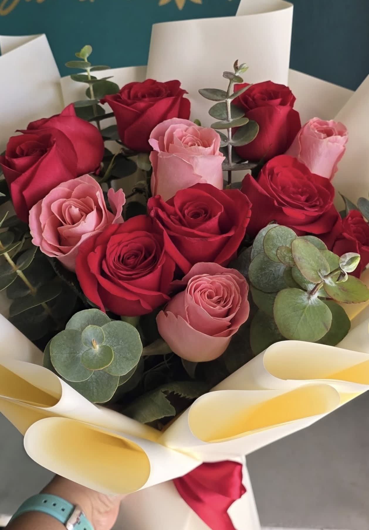 Bouquet of red and pink roses with eucalyptus wrapped in white paper