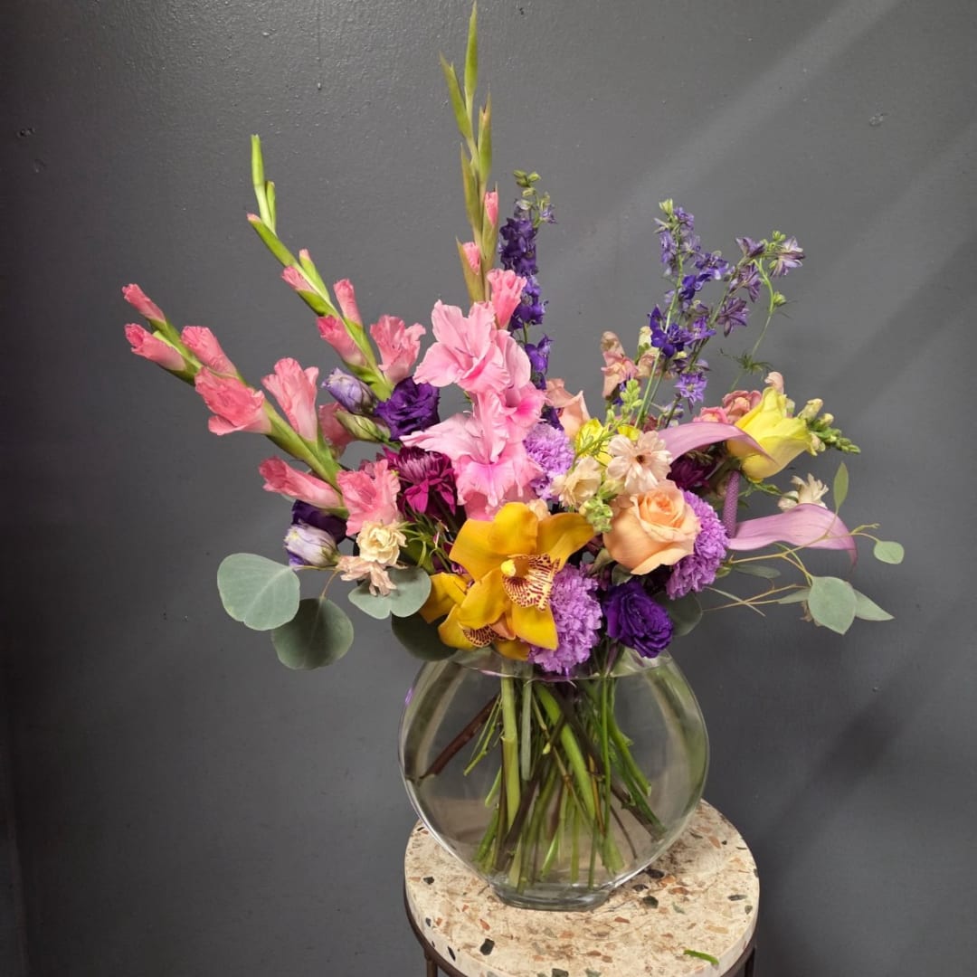 Colorful mixed bouquet in a clear glass vase with pink, purple, and yellow blooms