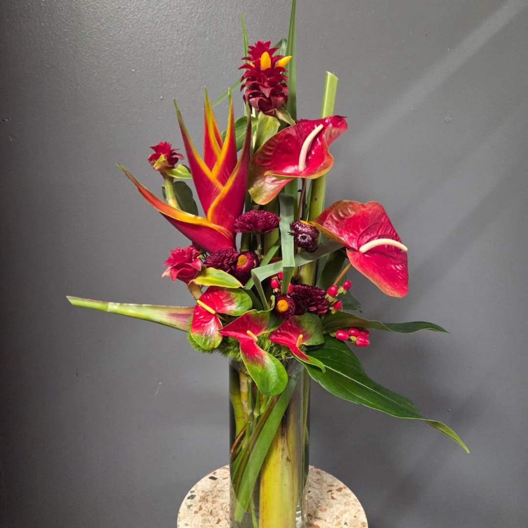 Tropical floral arrangement with red anthuriums in a glass vase