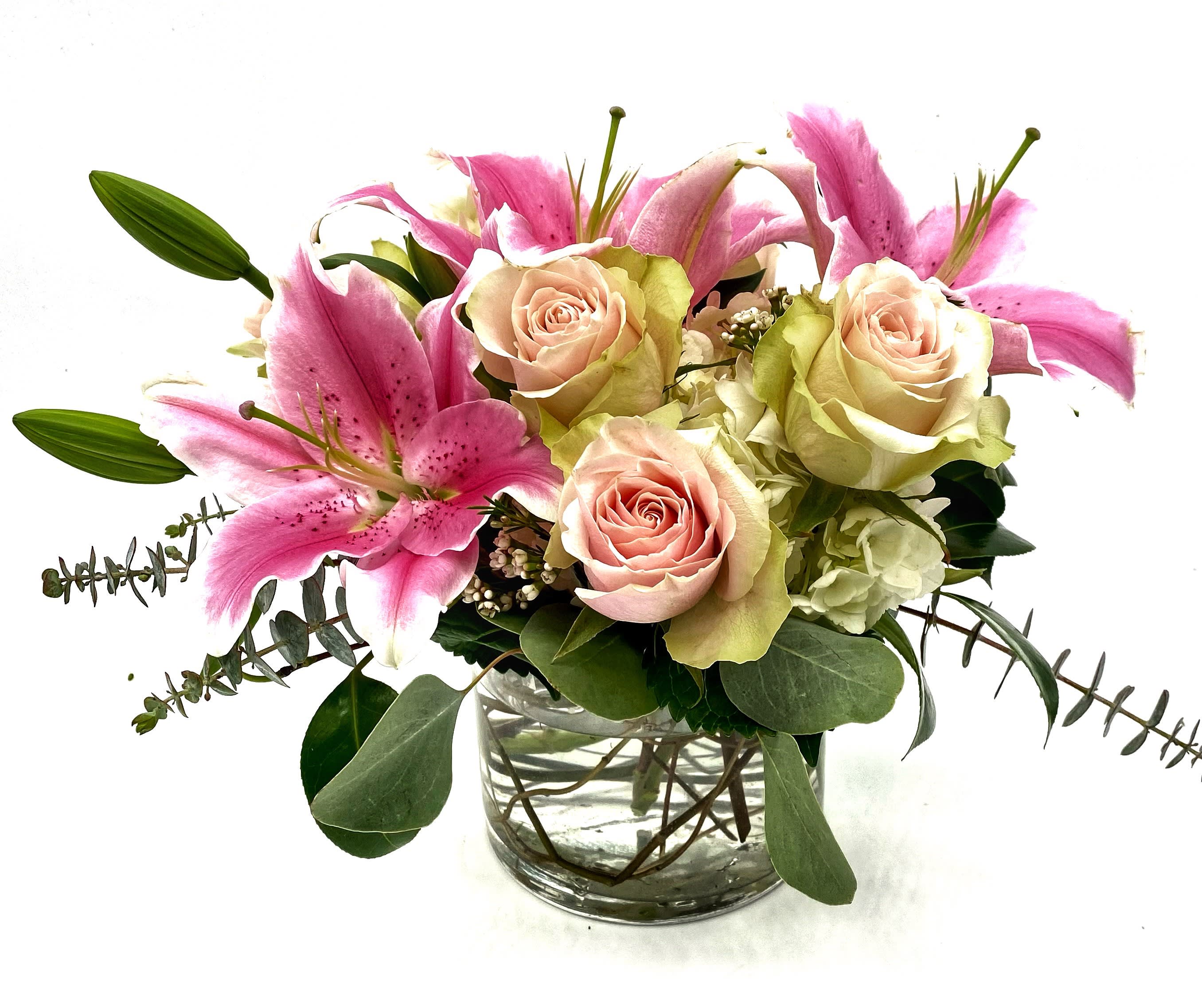 Pink lilies and pale roses arranged in a clear glass vase