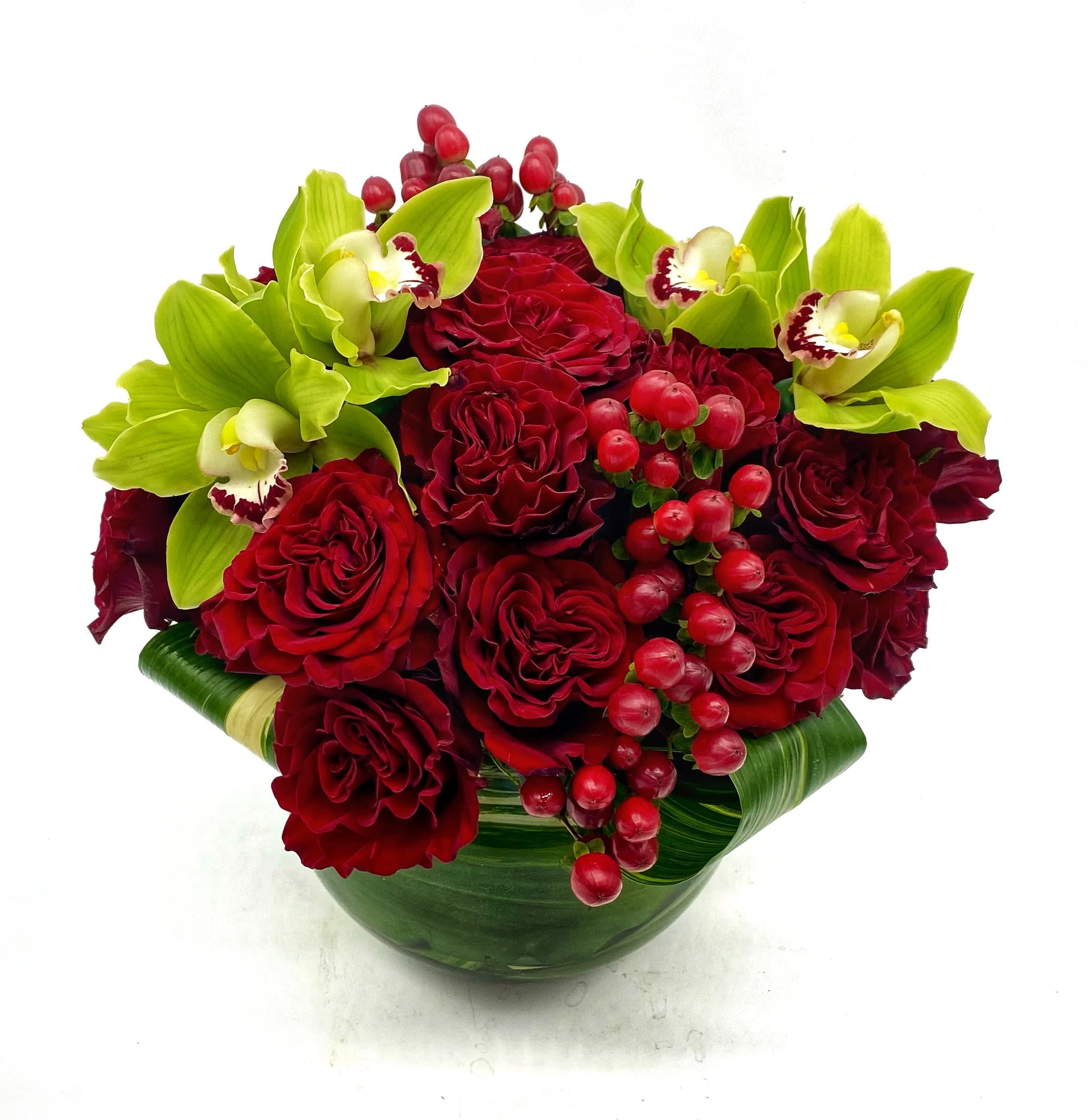 Lux - Crimson &amp; Cymbids - Crimson &amp; Cymbid is a dramatic, modern take on the classic rose arrangement. Featuring the striking contrast of deep red Heart roses and vibrant lime green cymbidium orchids, accented with rich red hypericum berries, this compact design is styled low and lush for maximum impact. A bold expression of color and elegance, it’s a true standout in the Lux by R. Bloom’s collection.
