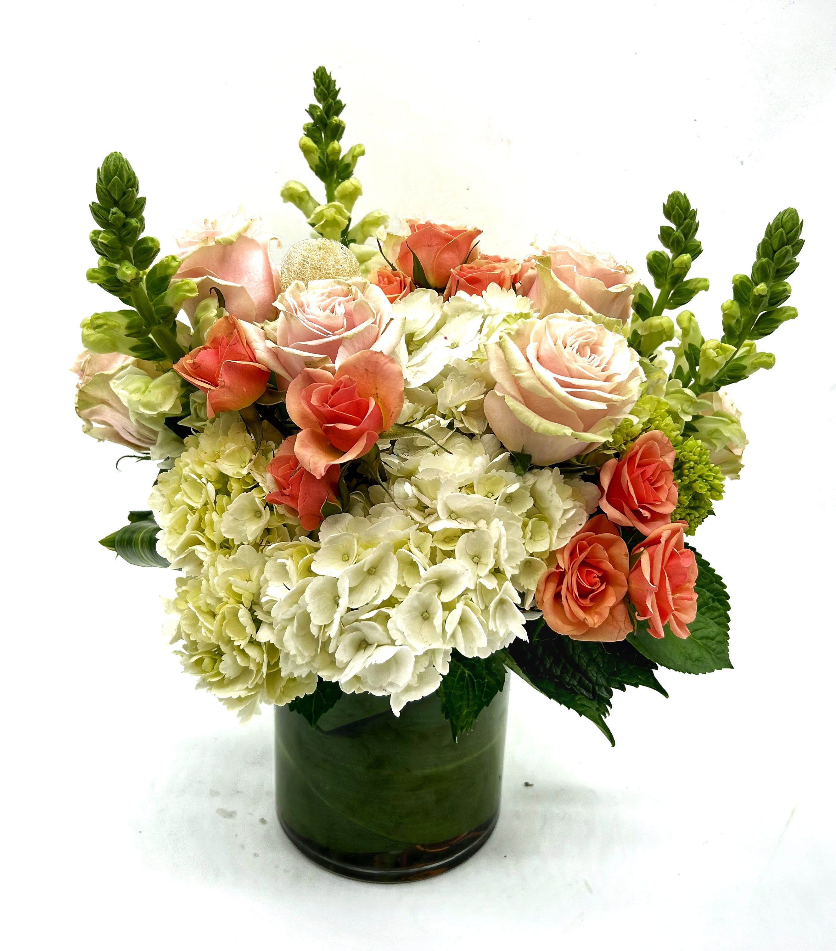Pink roses and white hydrangeas in a green glass vase