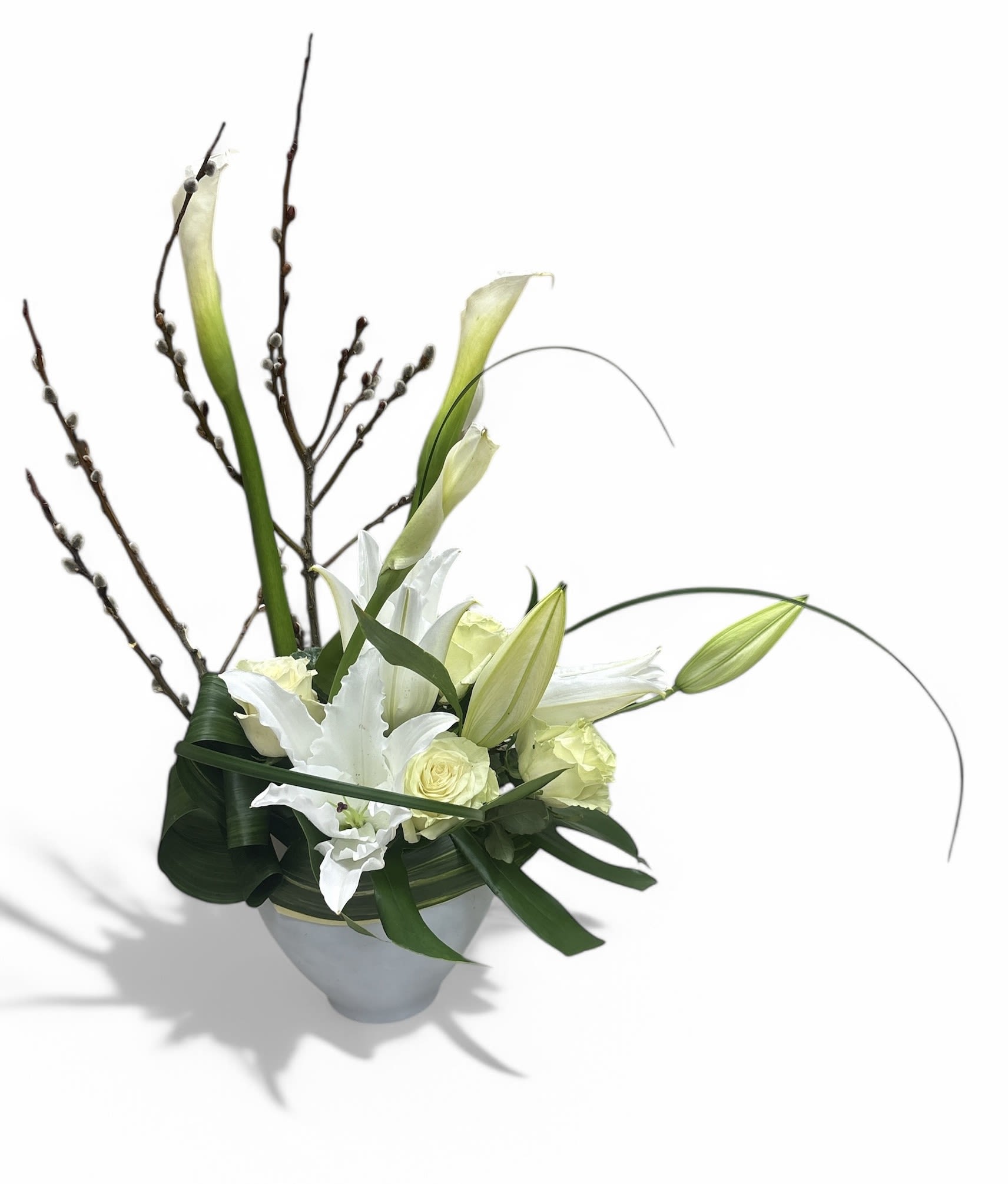 White calla lilies and roses in a white vase with tall branches