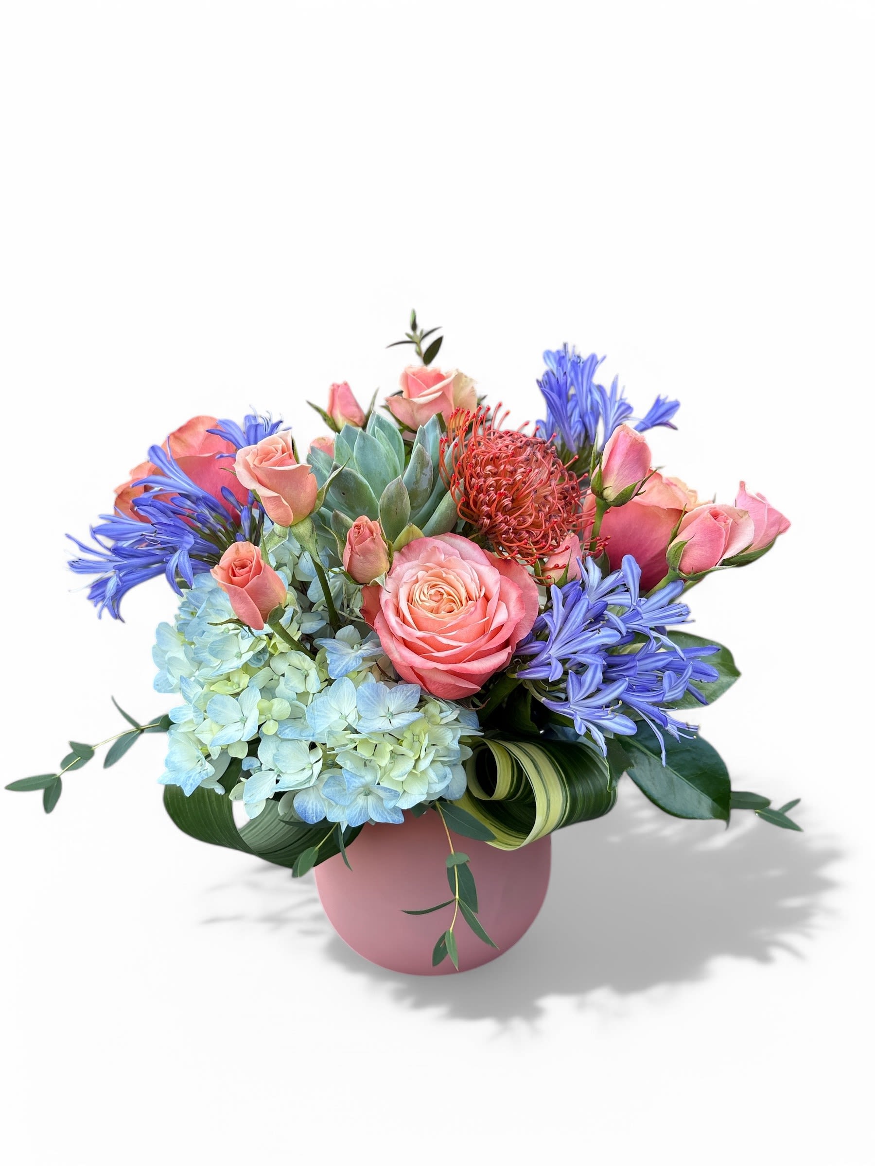 Pink roses and blue flowers arranged in a pink vase