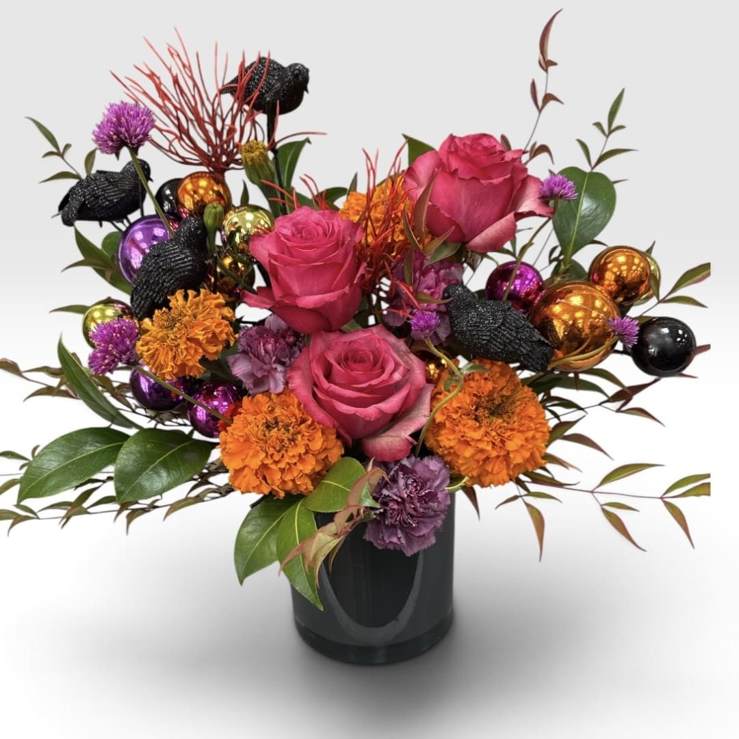 Pink roses and orange flowers in a black vase with decorative ornaments