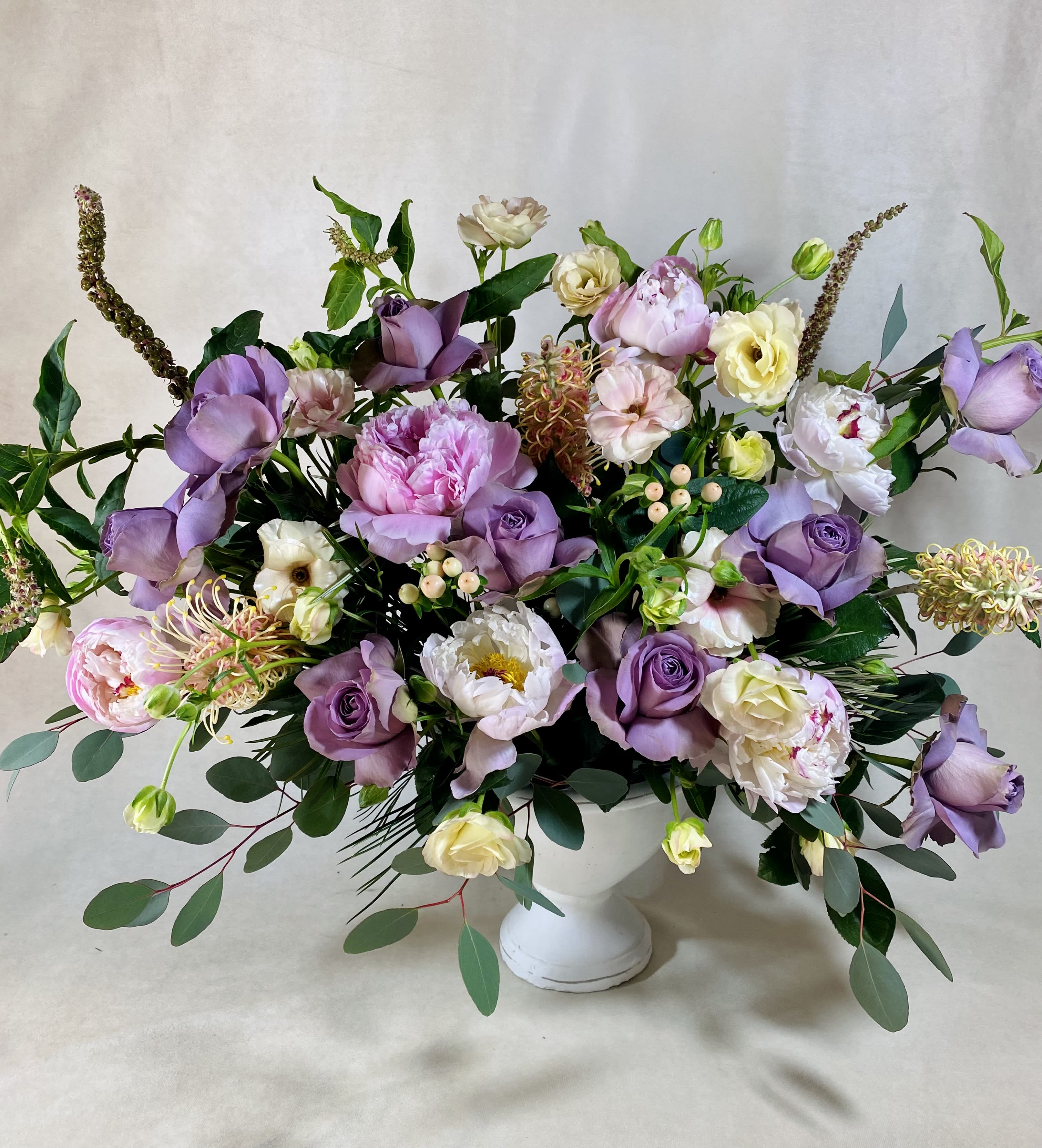 Lavender and white floral arrangement in a white pedestal vase