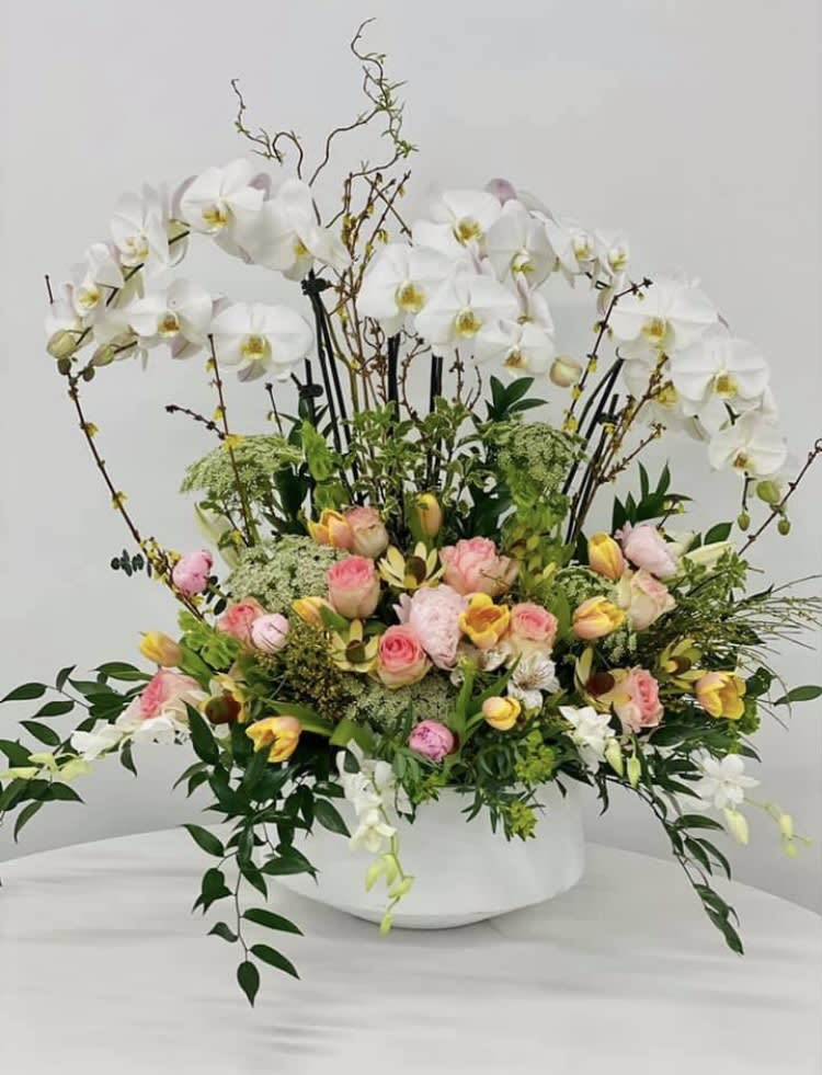 Large floral arrangement with white orchids and pink roses in a white vase