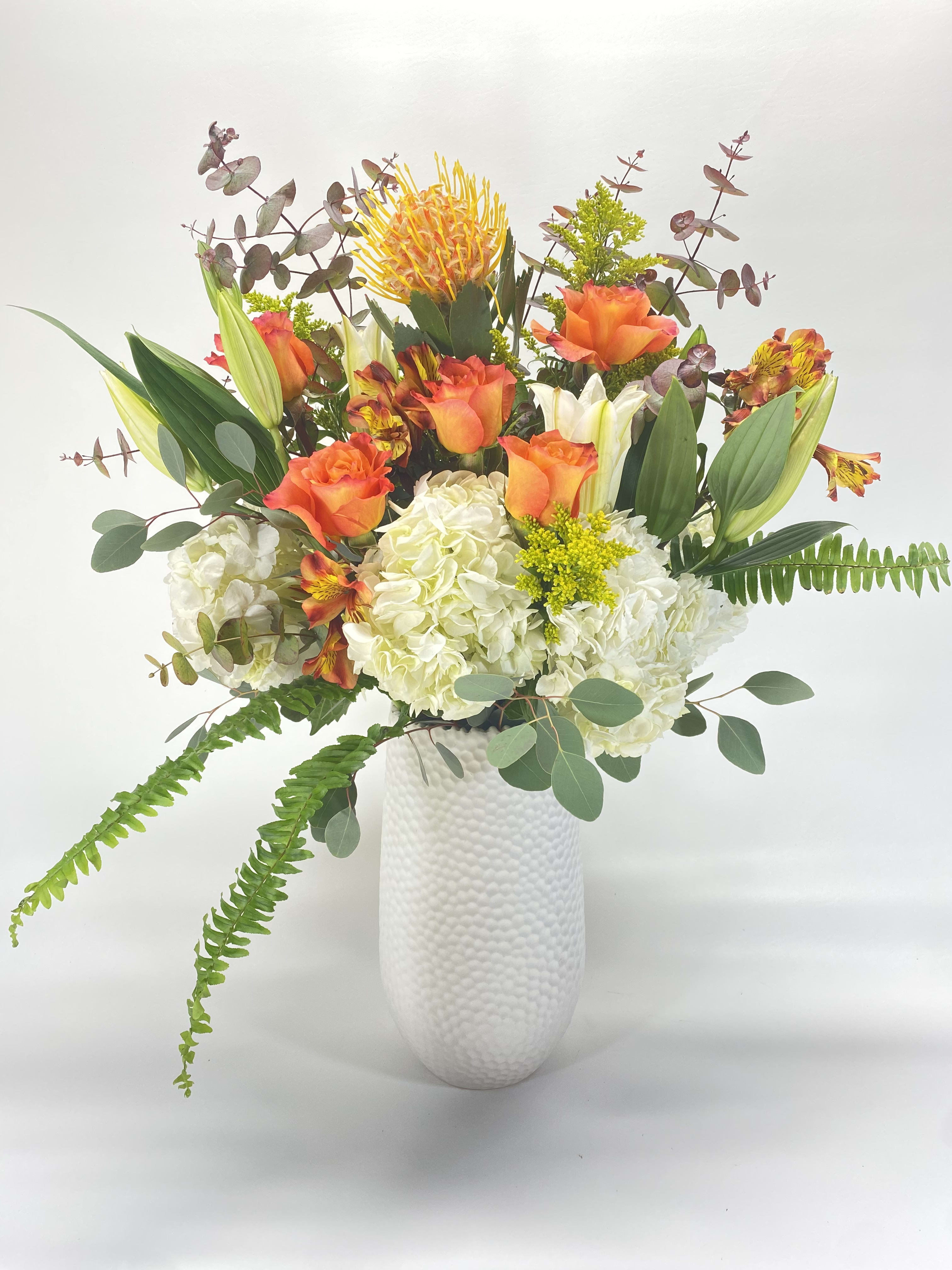 Orange and white floral arrangement in a white vase