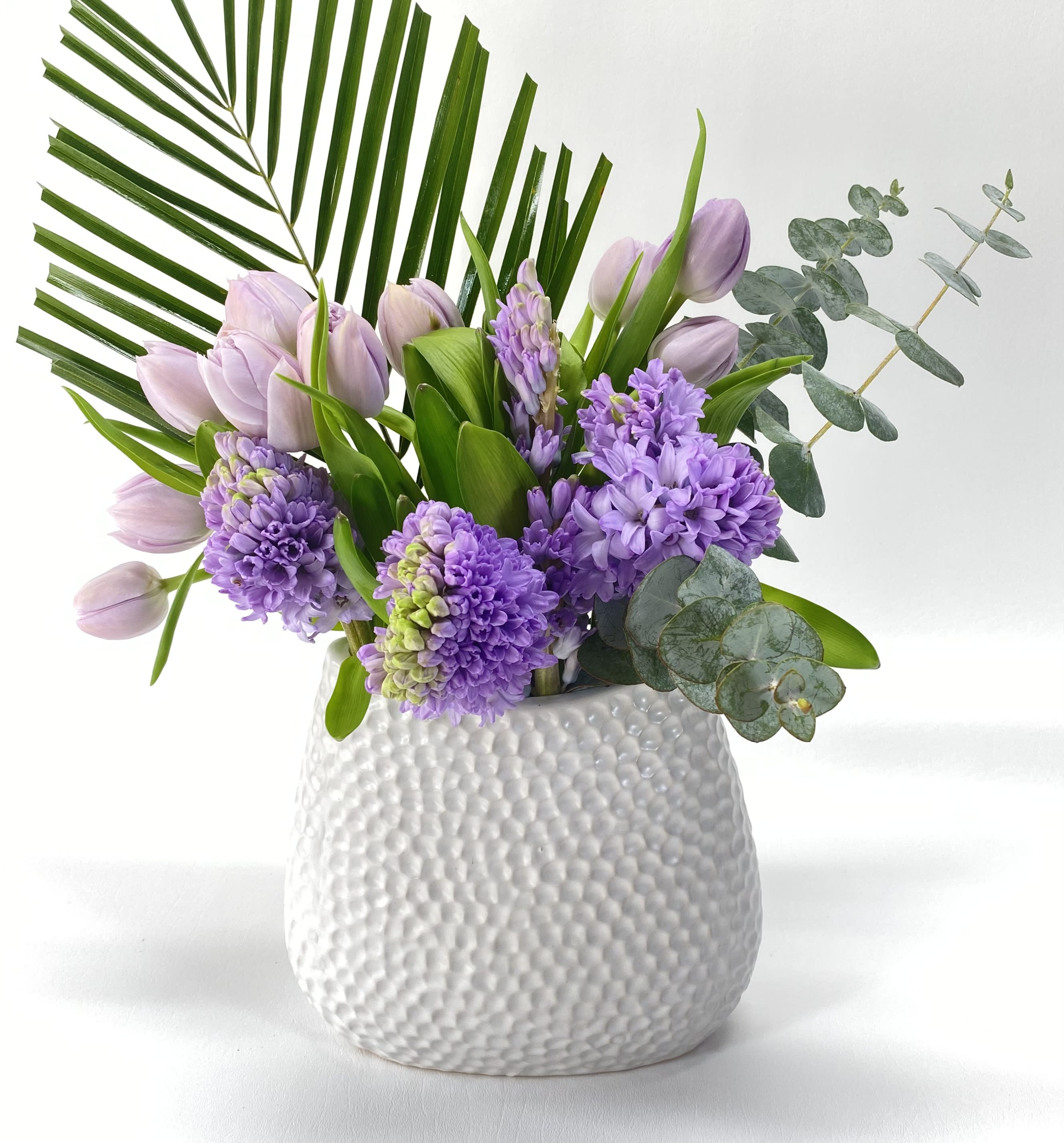 Lavender tulips and purple hyacinths in a white textured vase
