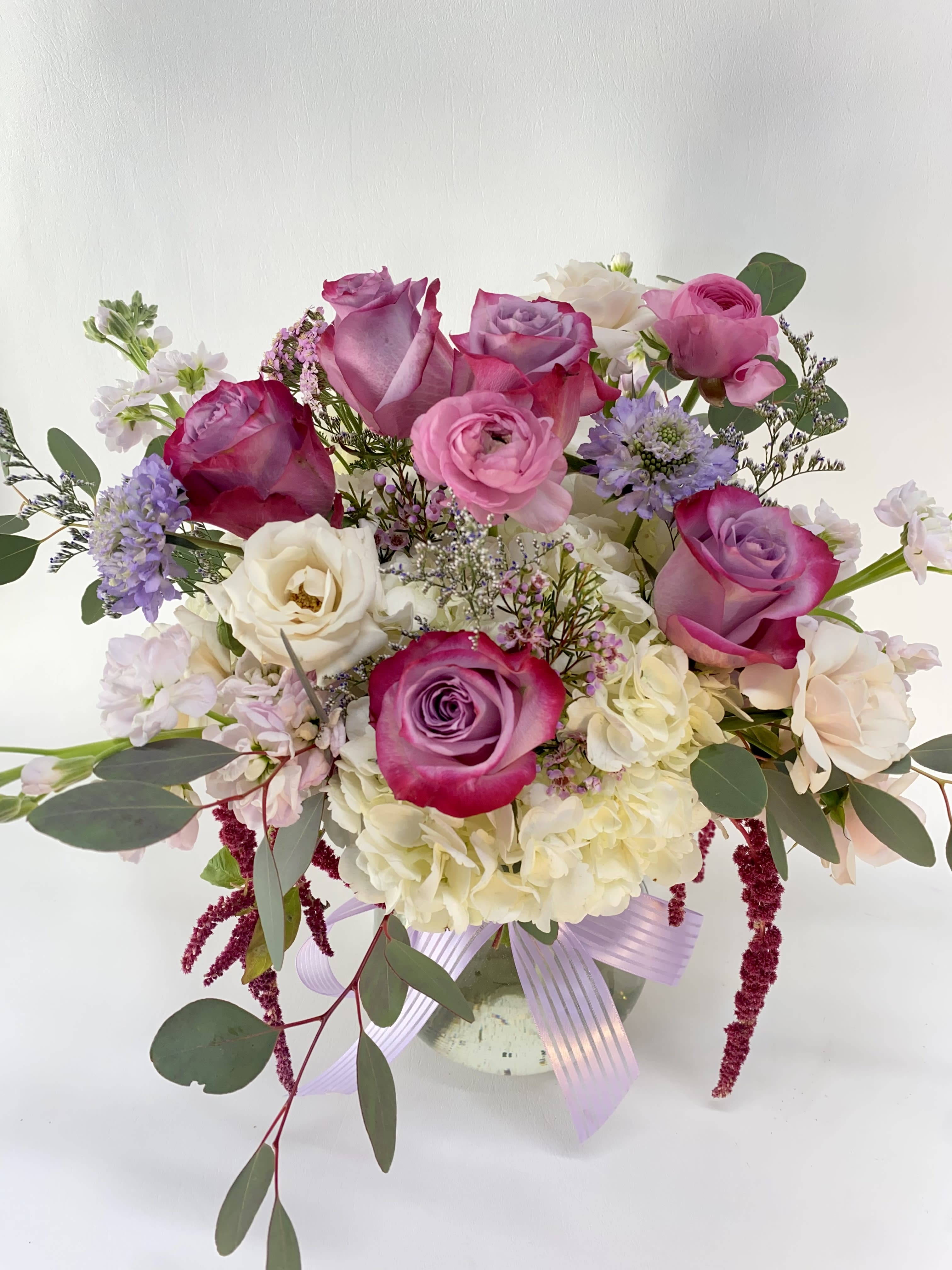 Bouquet of pink and white roses in a glass vase with a lavender ribbon