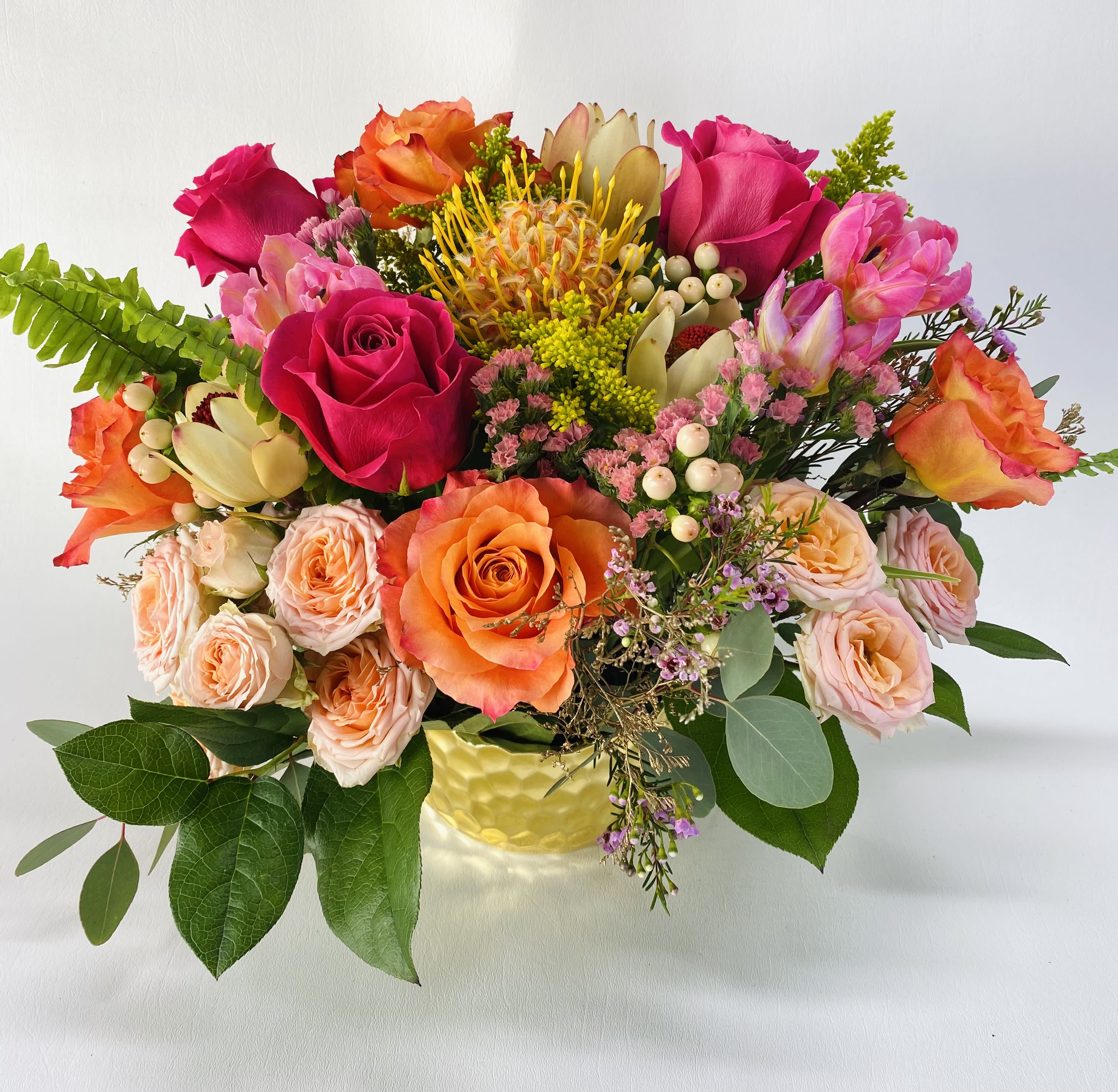 Mixed bouquet of roses and tropical blooms in a yellow vase