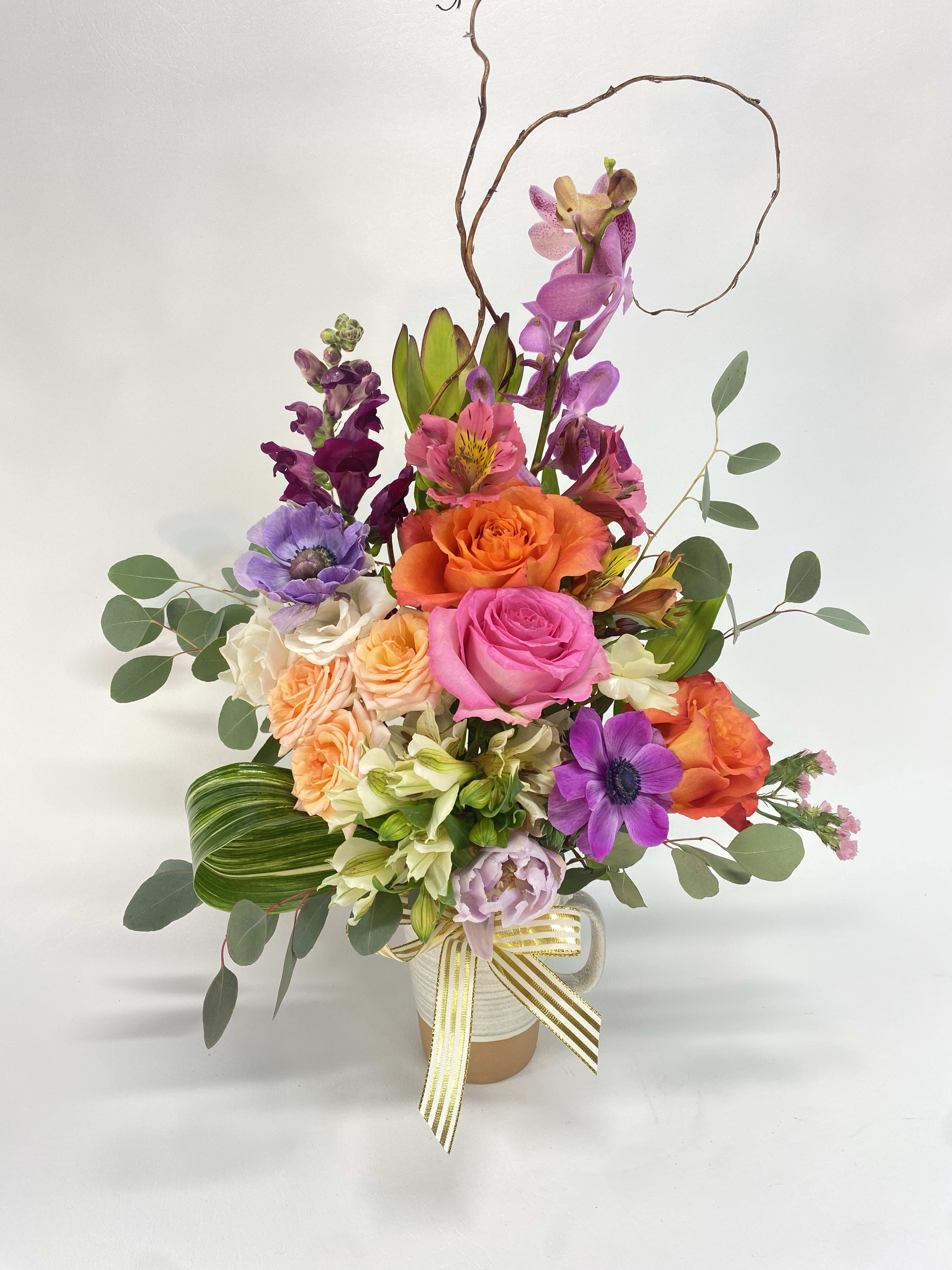 Colorful mixed flower arrangement in a white vase with ribbon