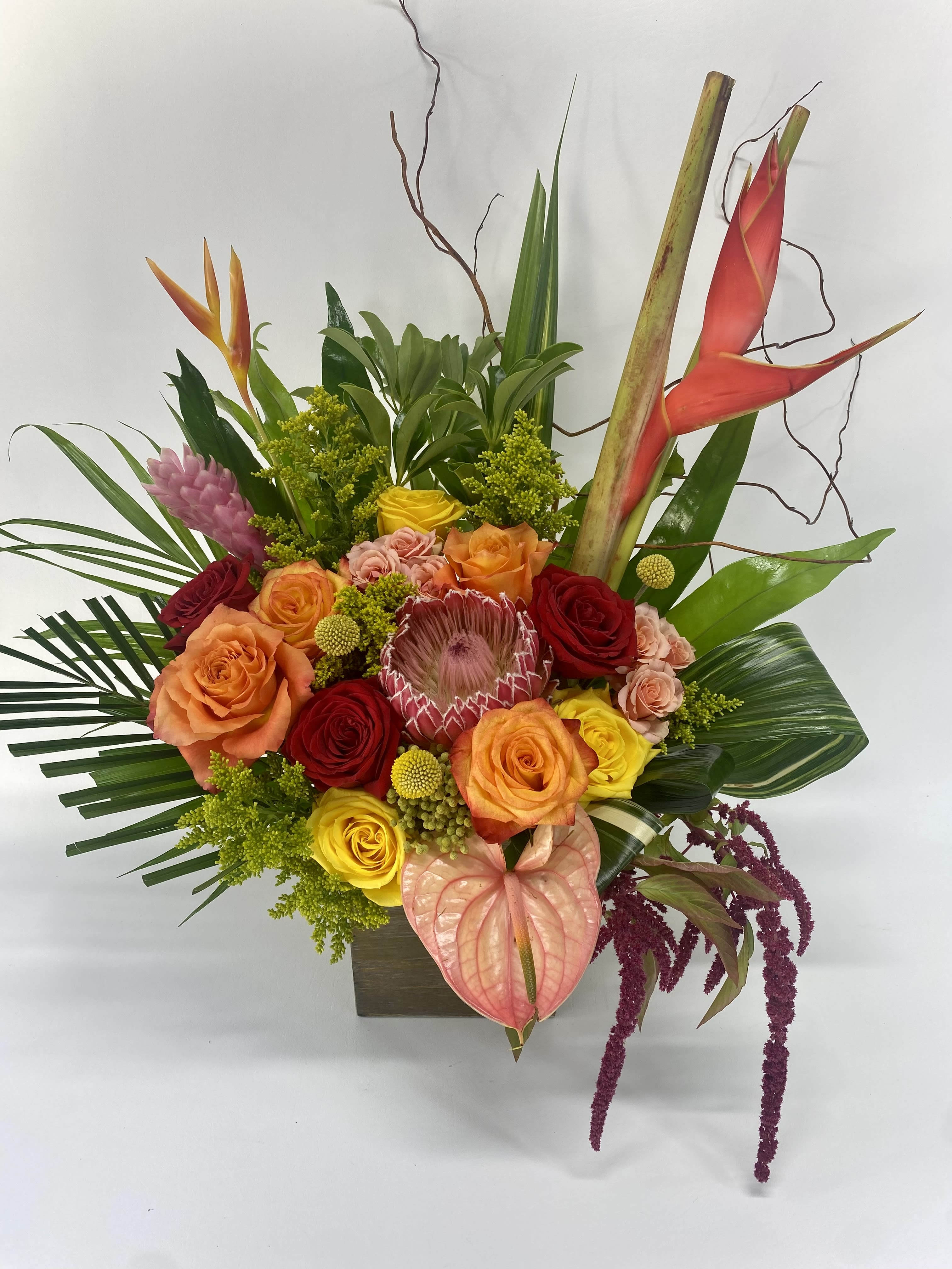 Tropical bouquet with roses, anthurium, and heliconia in a square vase