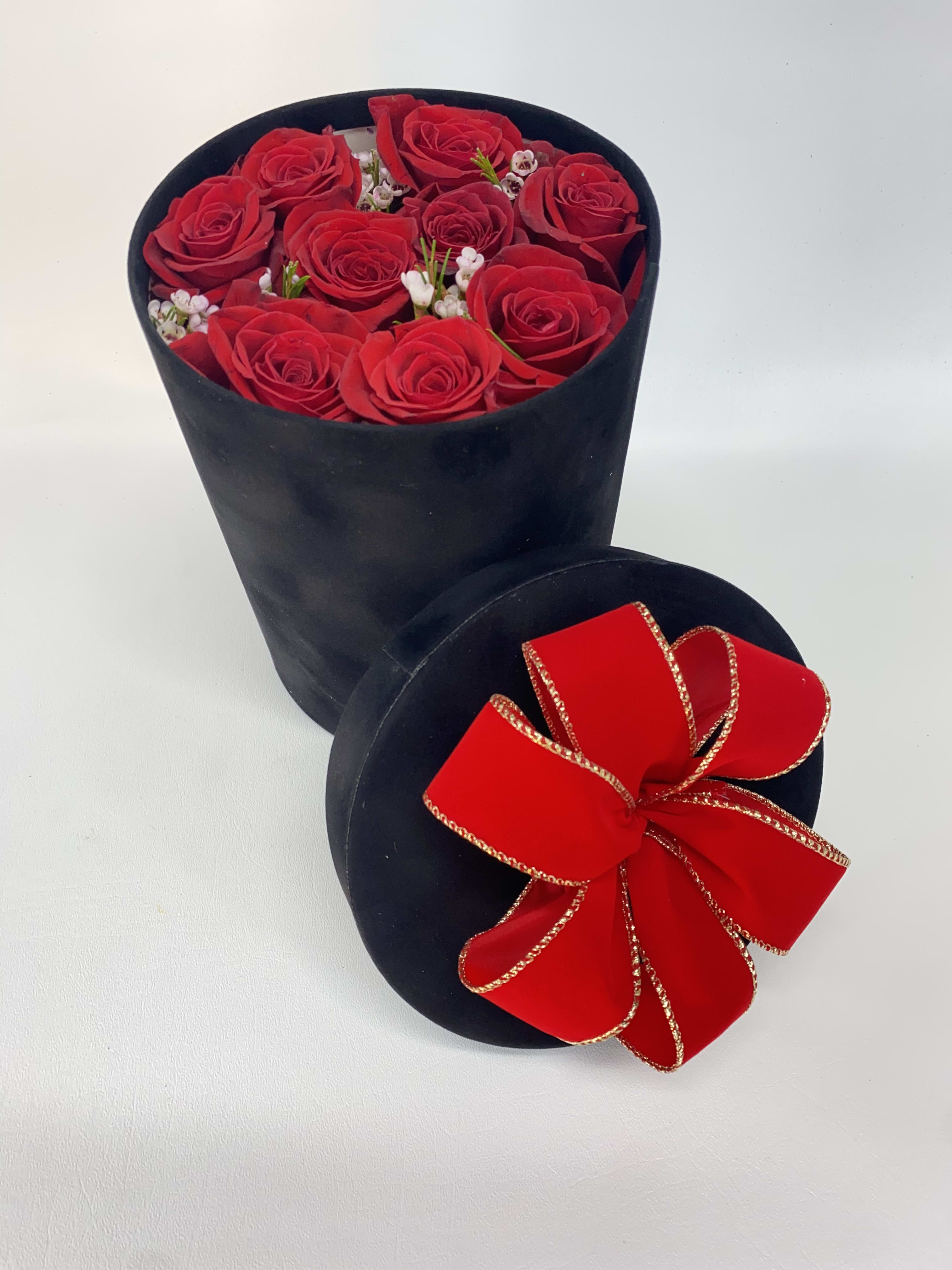 Red roses in a black round box with a red ribbon bow