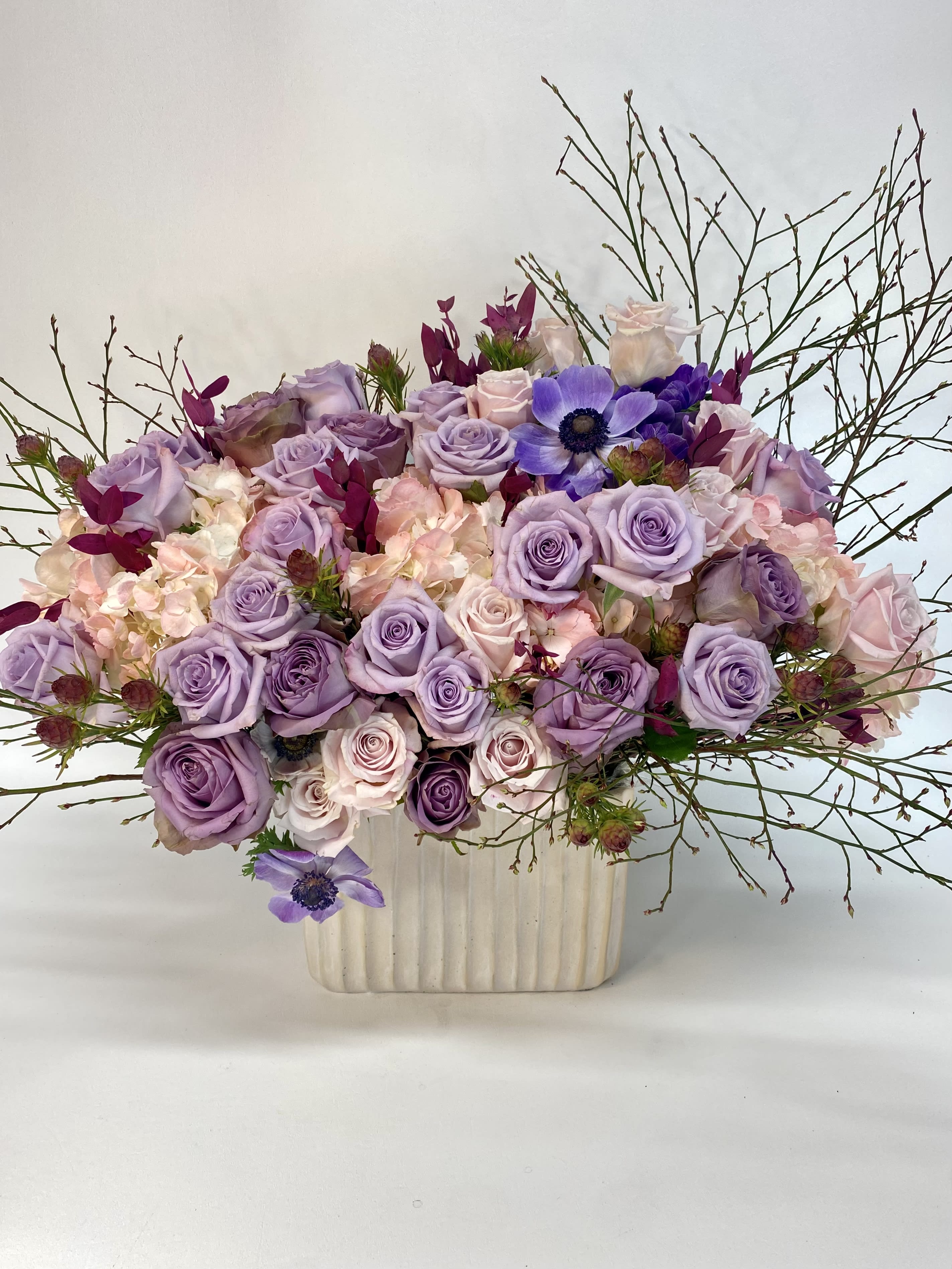 Lavender and blush rose arrangement in a cream vase