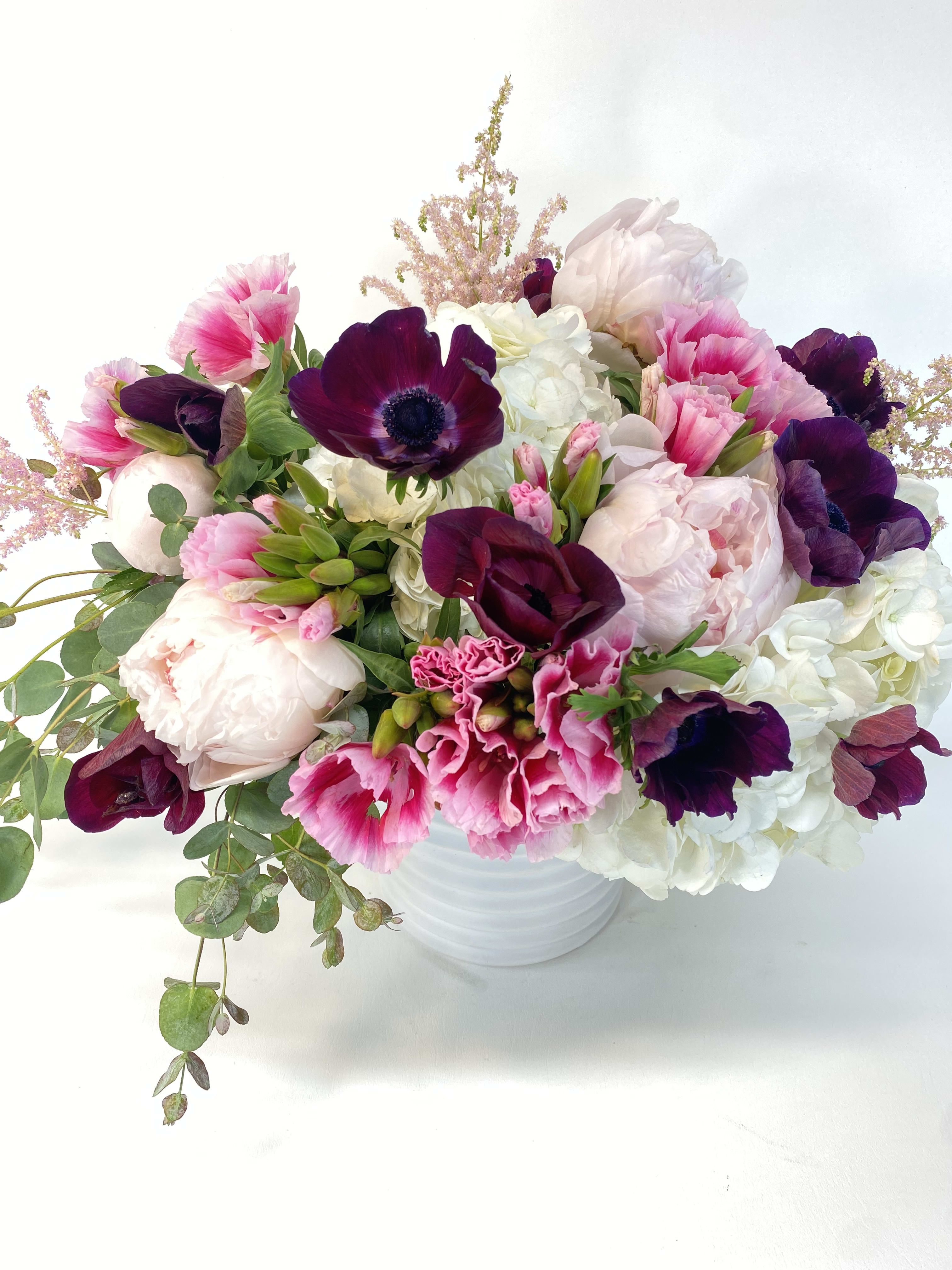 Pink and white bouquet with dark purple blooms in a white vase