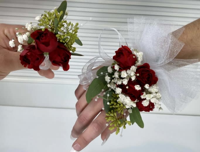 Red rose corsages with white baby's breath and tulle ribbon