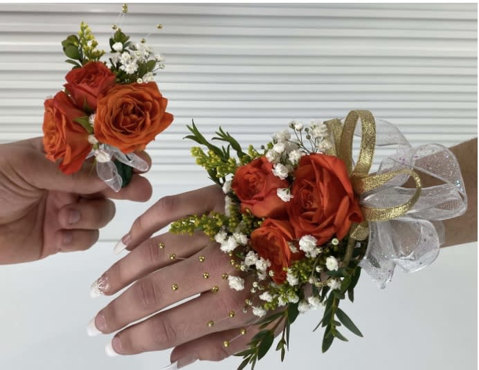 Orange rose corsages with white baby's breath and gold ribbon