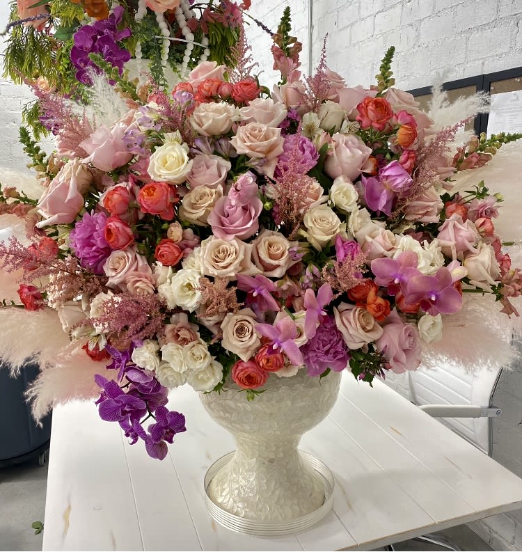 Large mixed bouquet of pink, cream, and purple flowers in a white vase