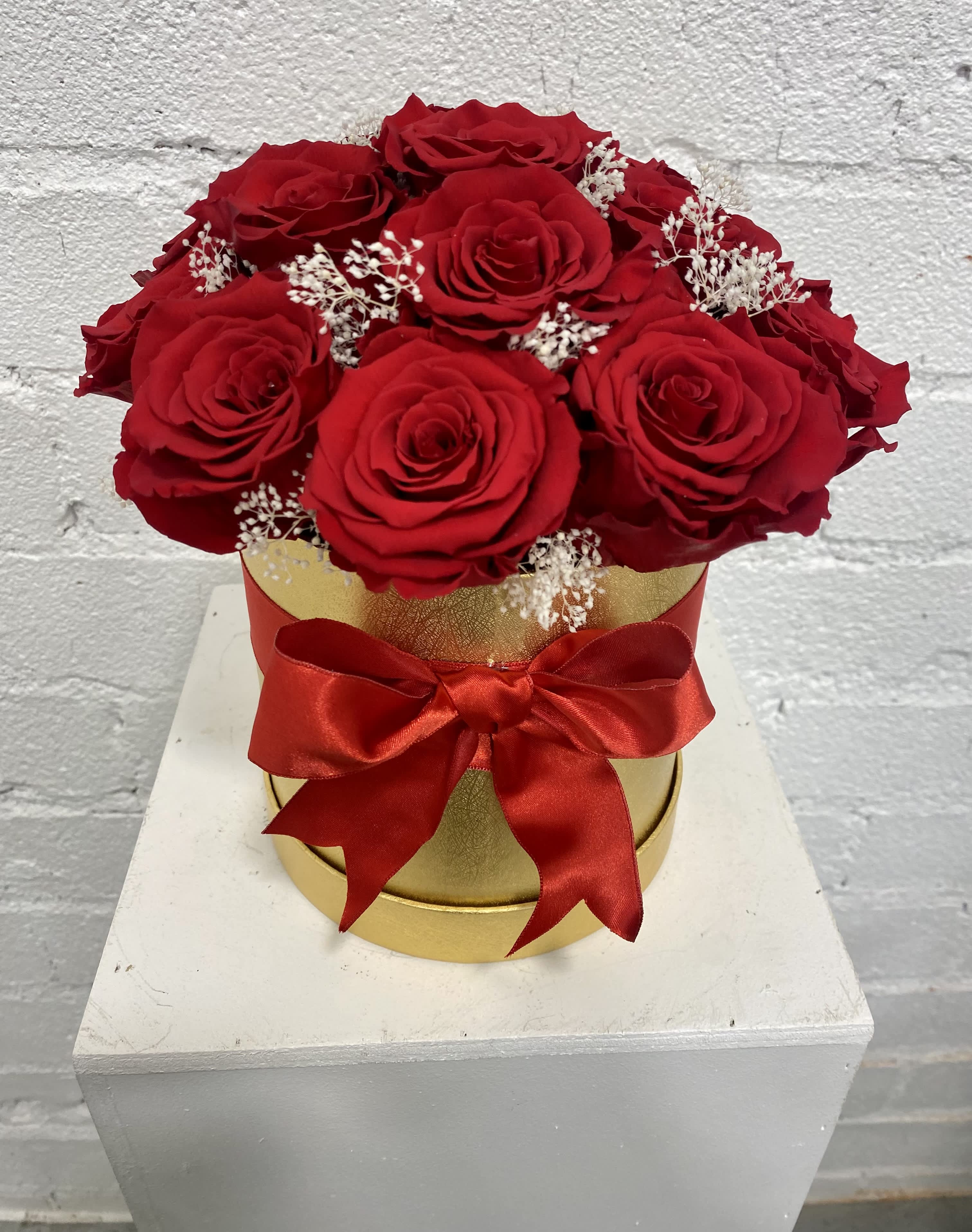 Red roses in a gold box with a red ribbon