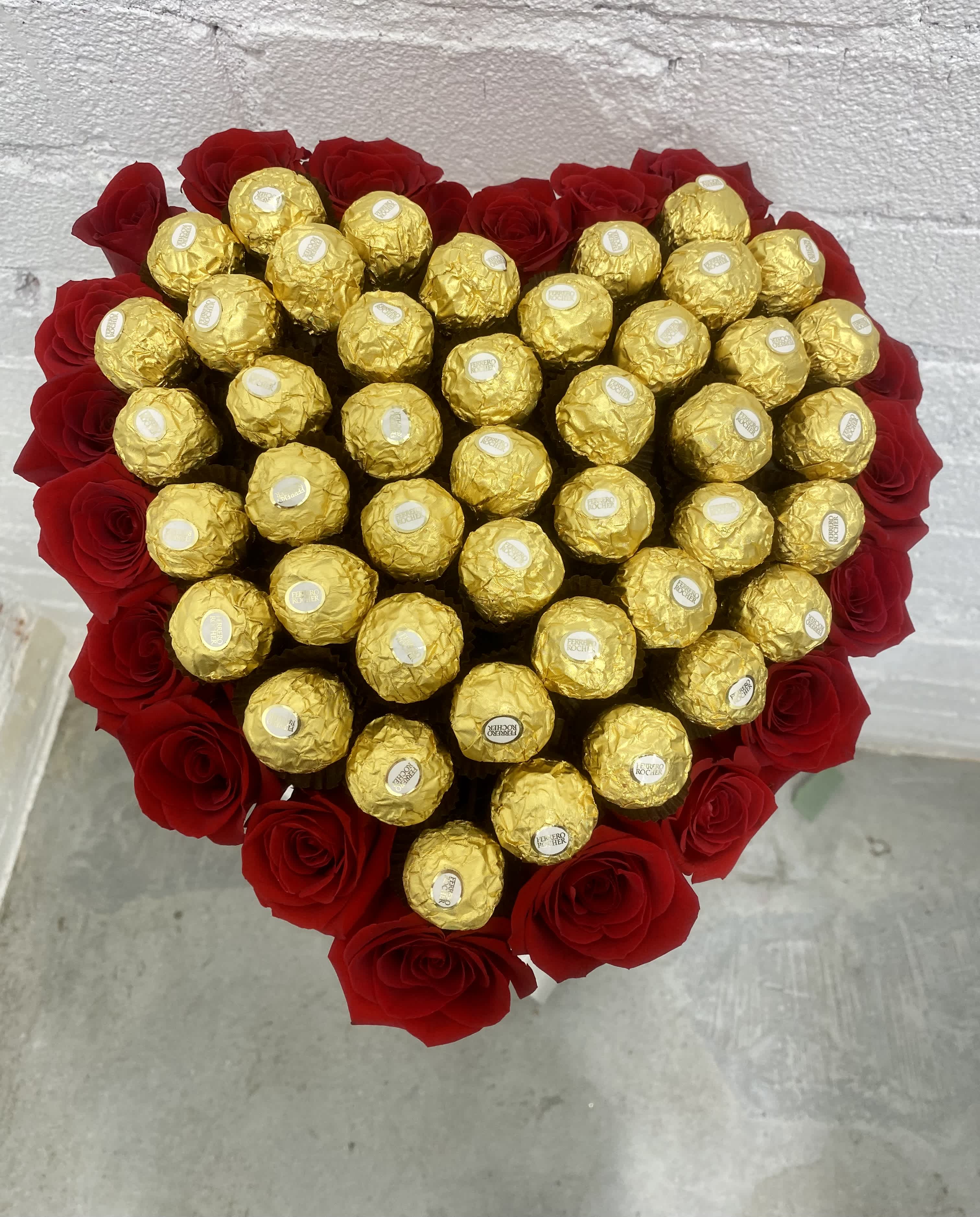 Heart-shaped bouquet of red roses with gold-wrapped chocolates