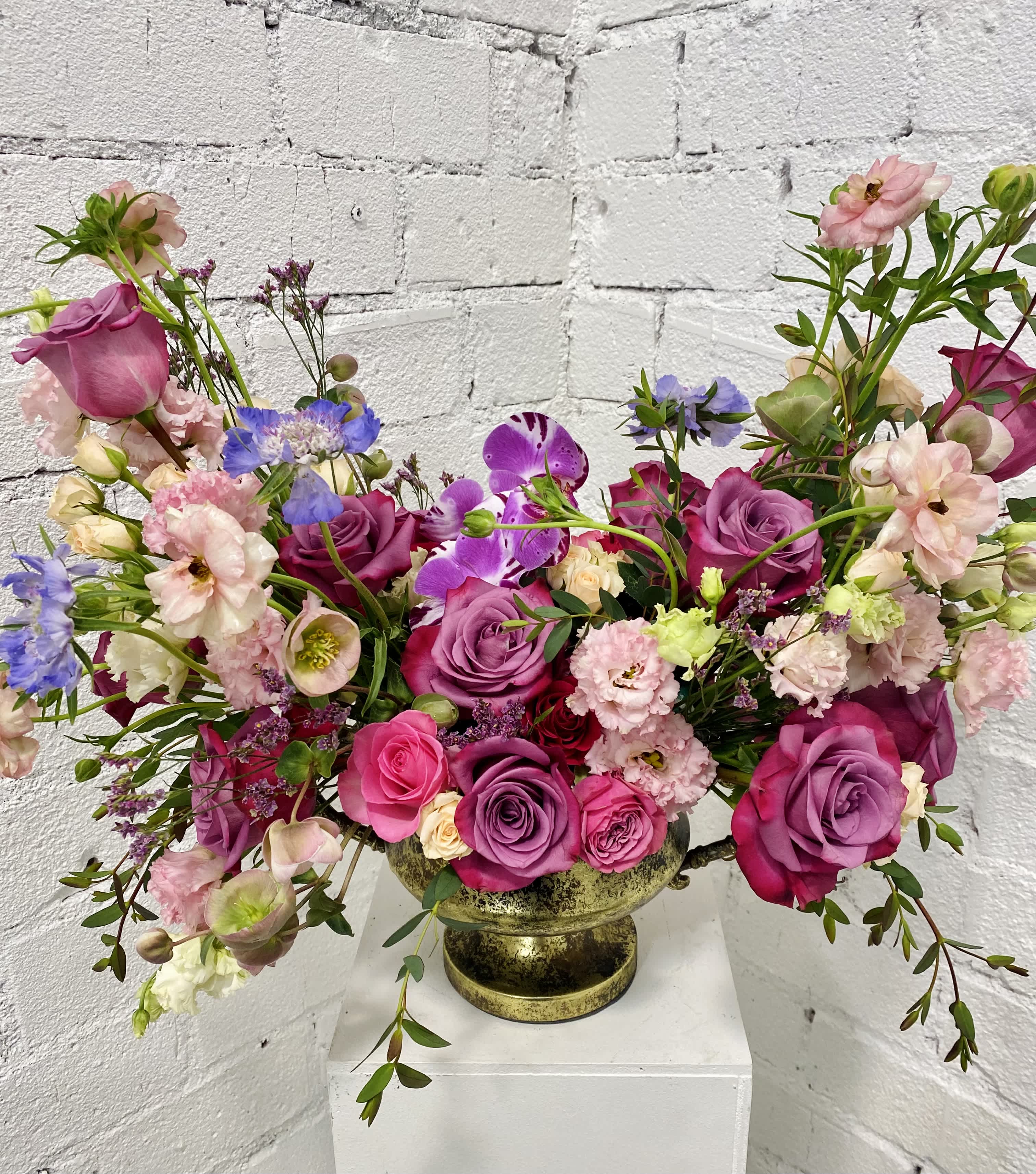 Mixed pink and purple floral arrangement in a gold vase
