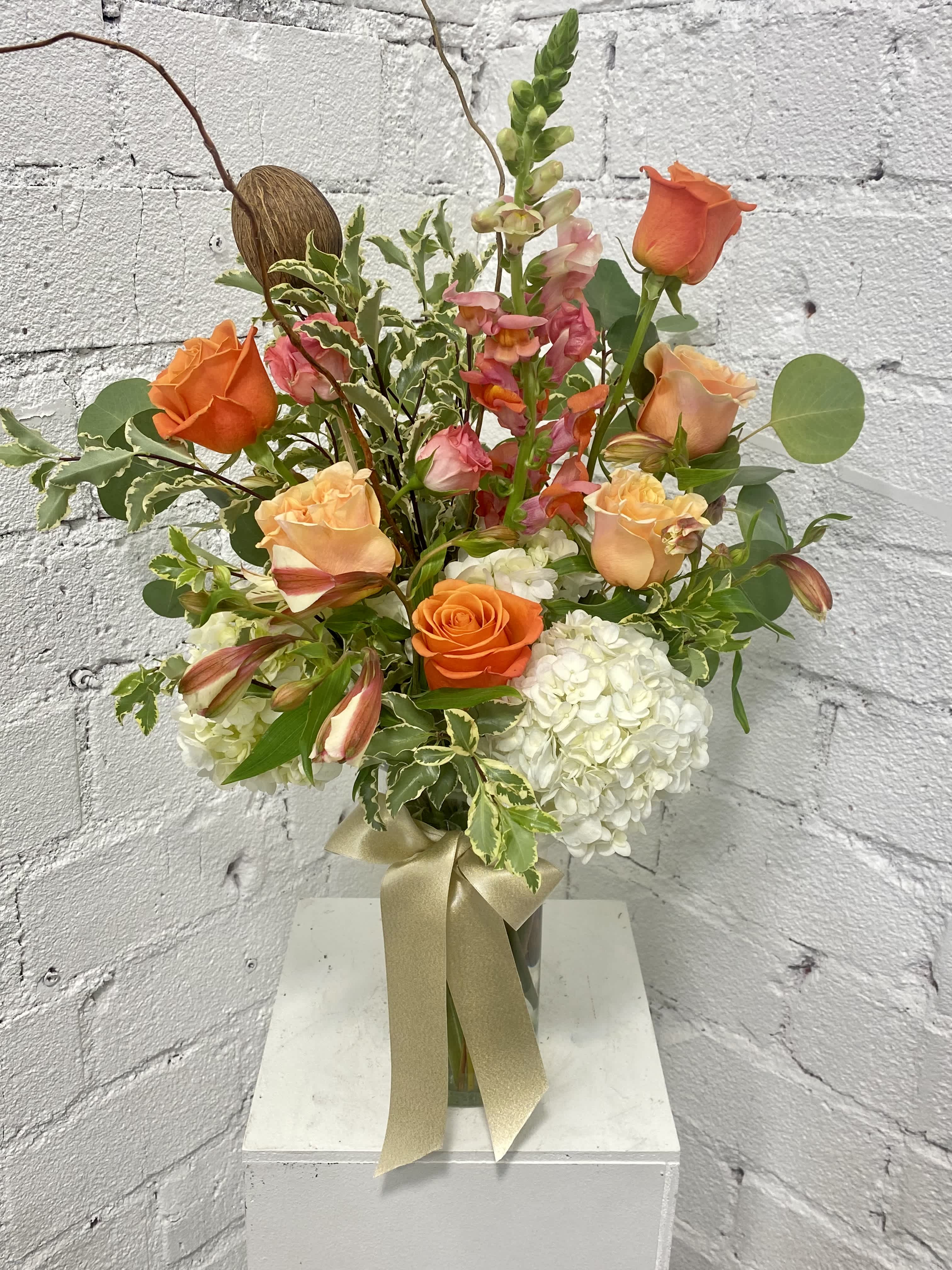 Orange and peach roses with white hydrangeas in a glass vase