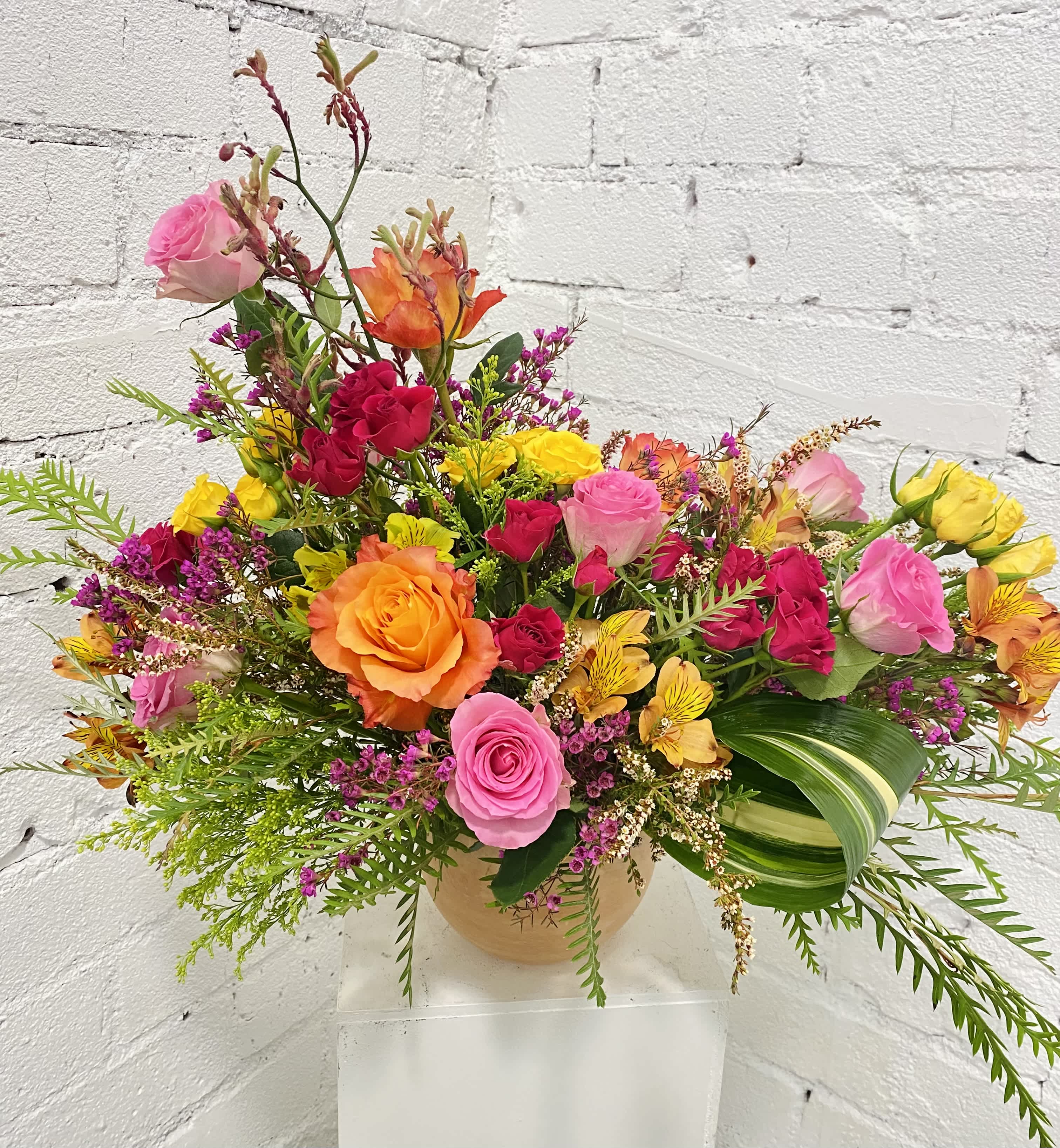 Colorful mixed bouquet of roses and small filler flowers in a round vase