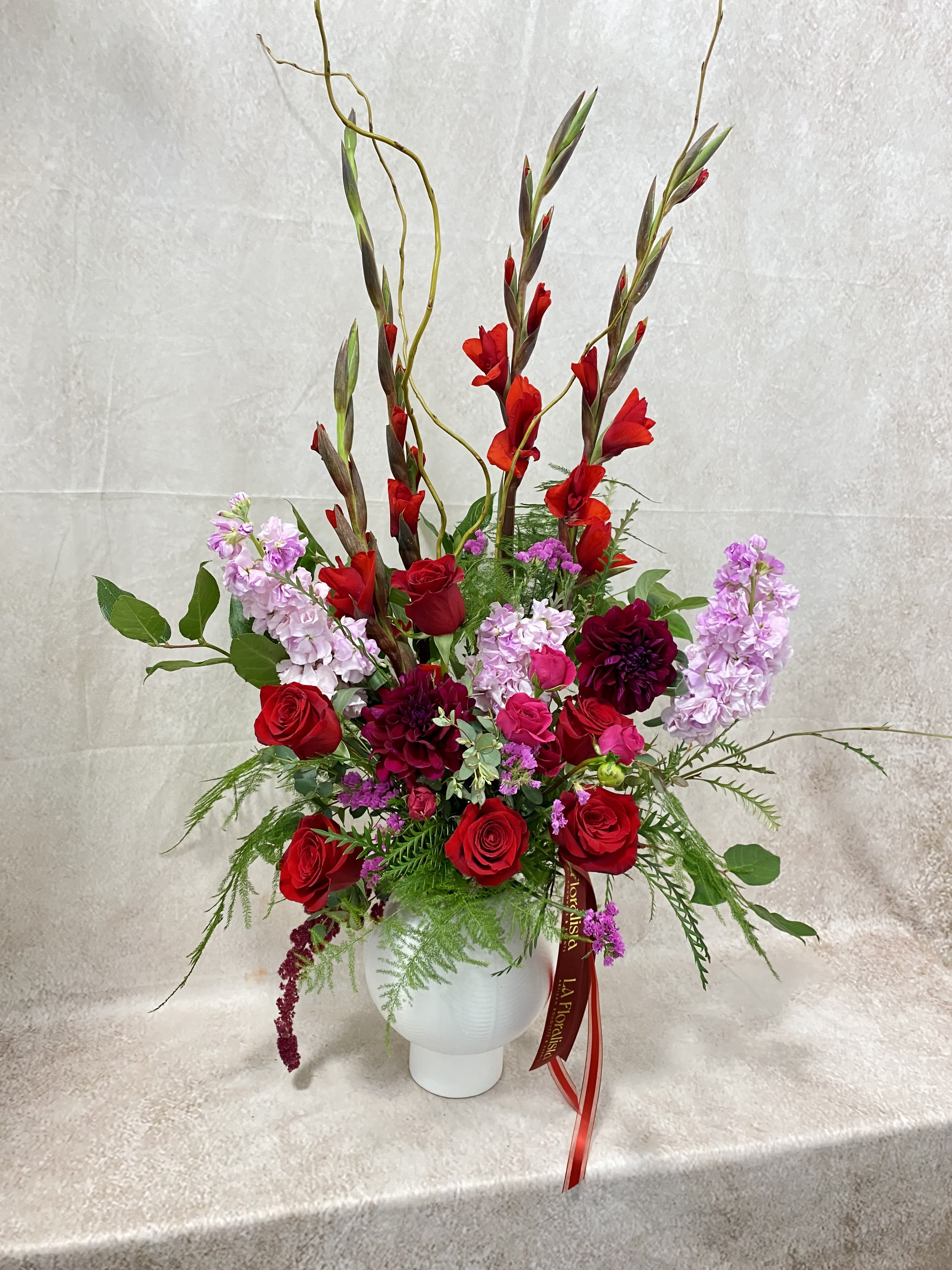 Tall red and pink floral arrangement in a white vase