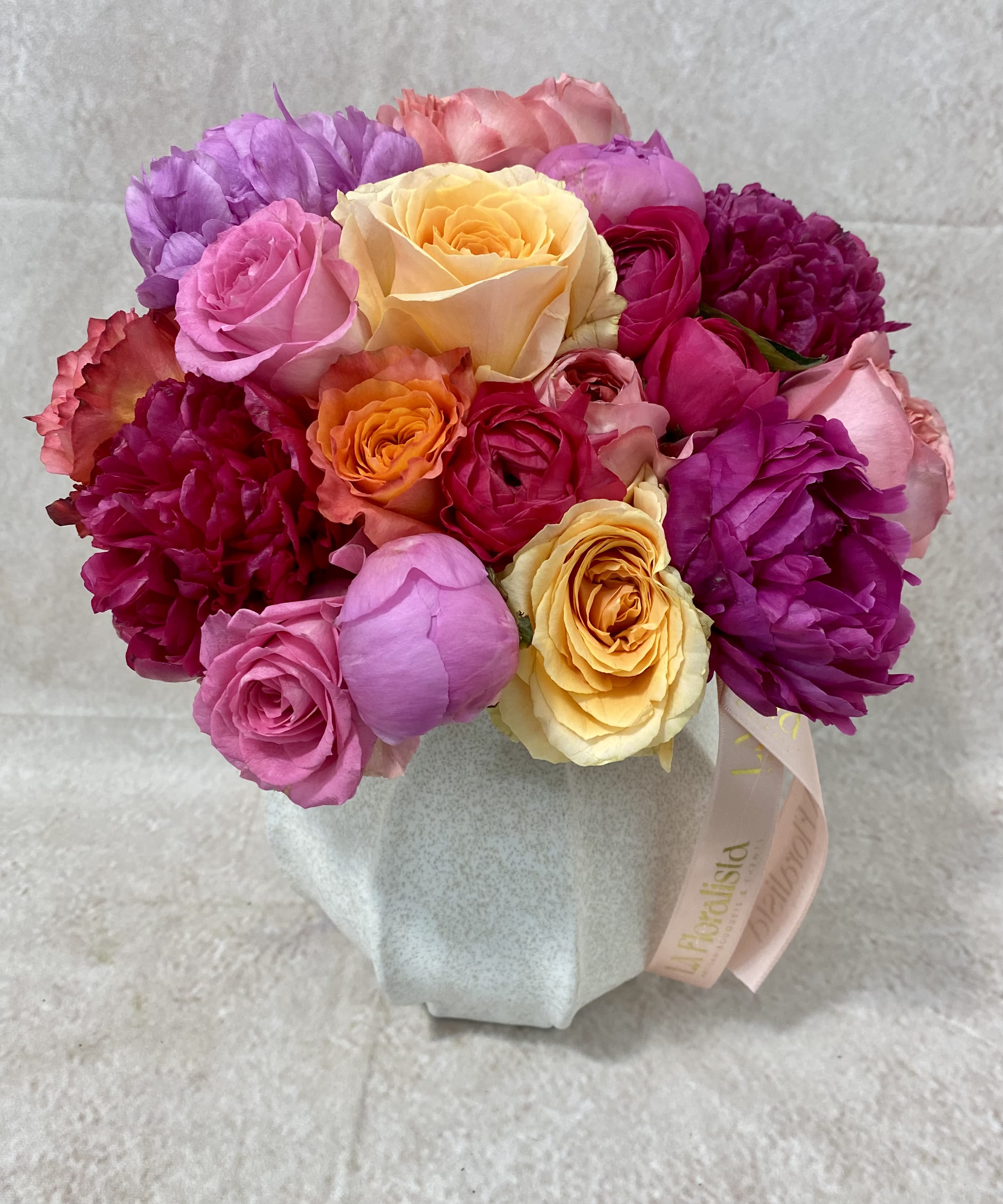 Mixed bouquet of pink, purple, and yellow roses in a wrapped base