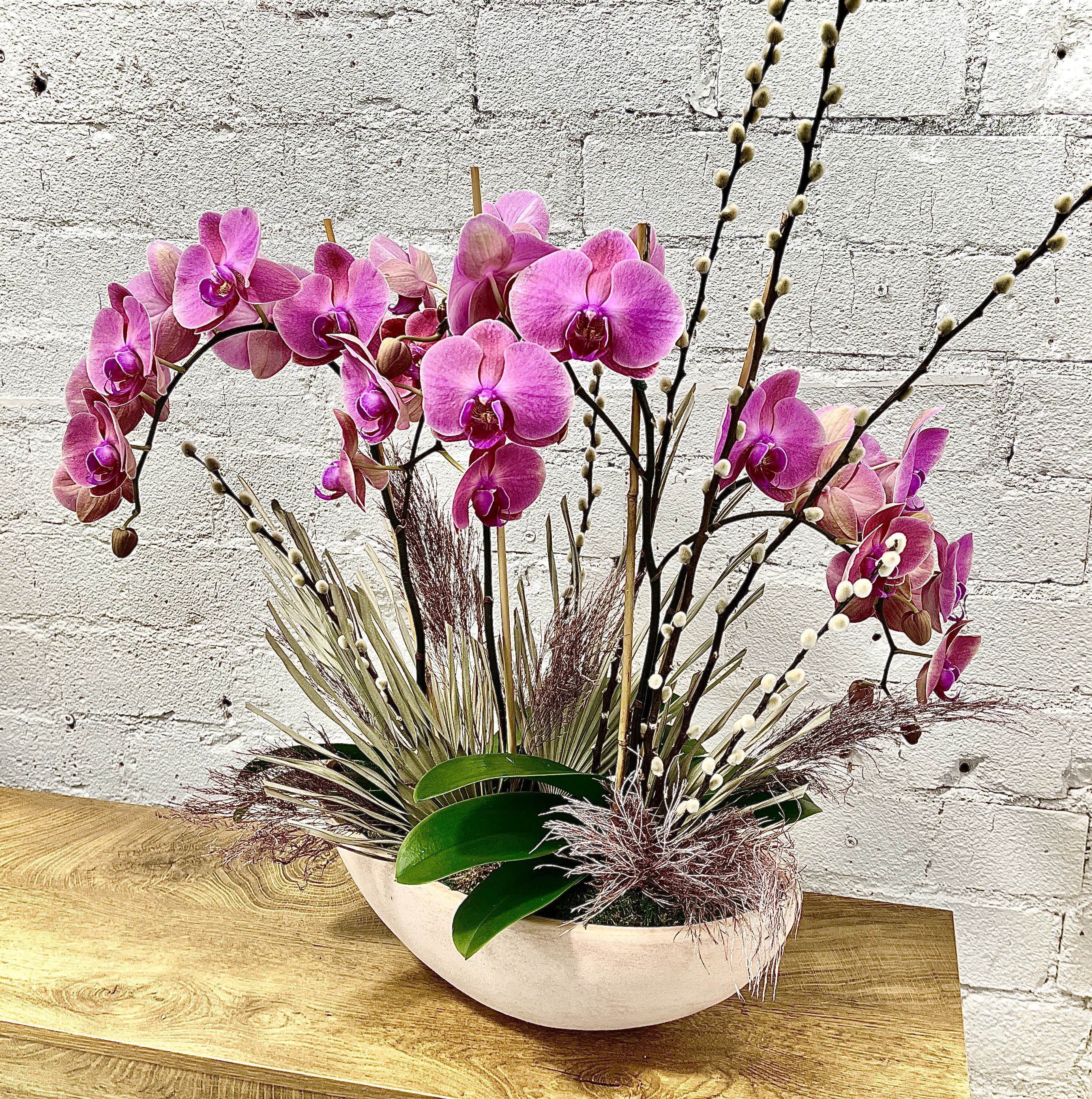 Pink orchid arrangement in a white oval bowl