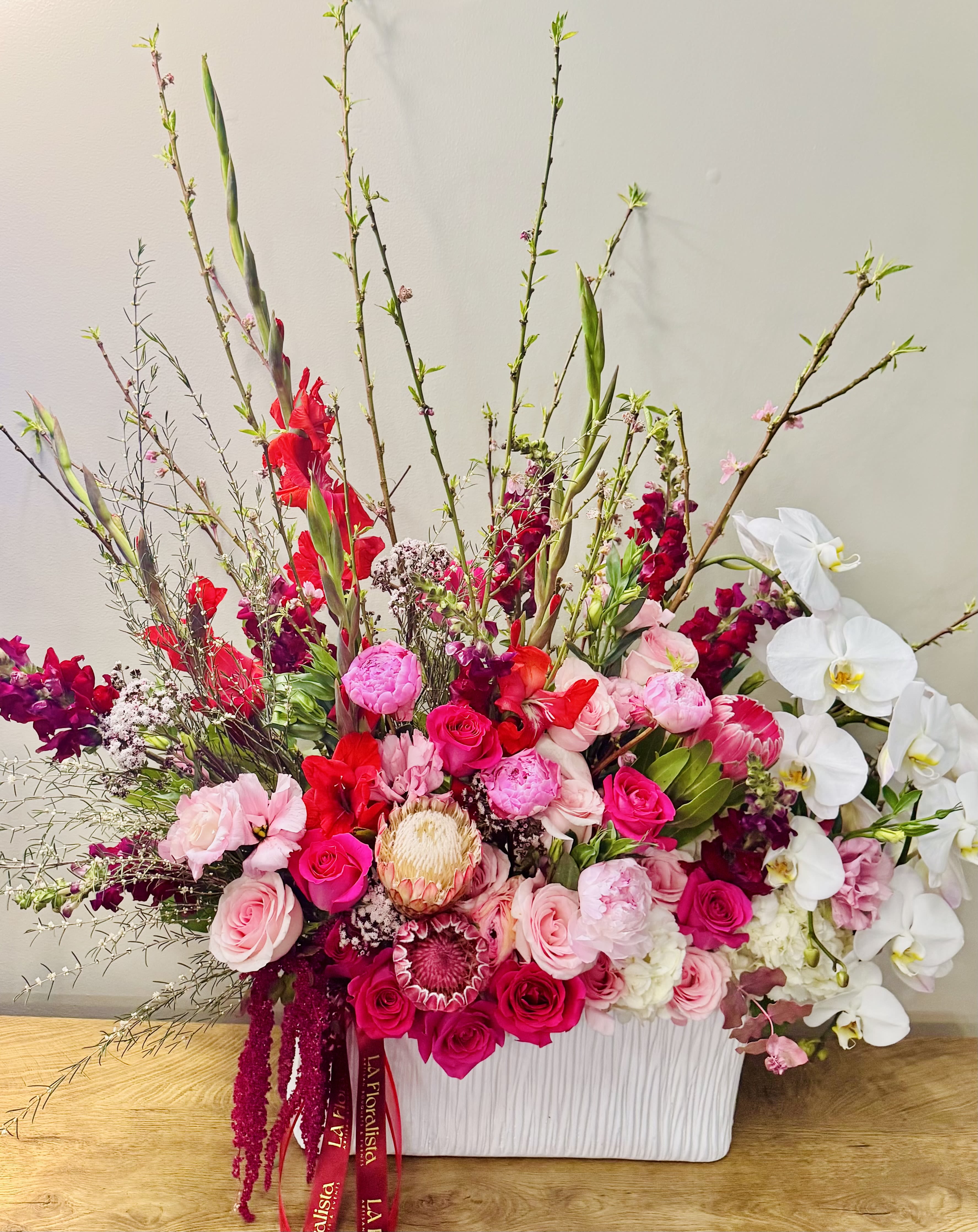 Large pink and white floral arrangement in a white container