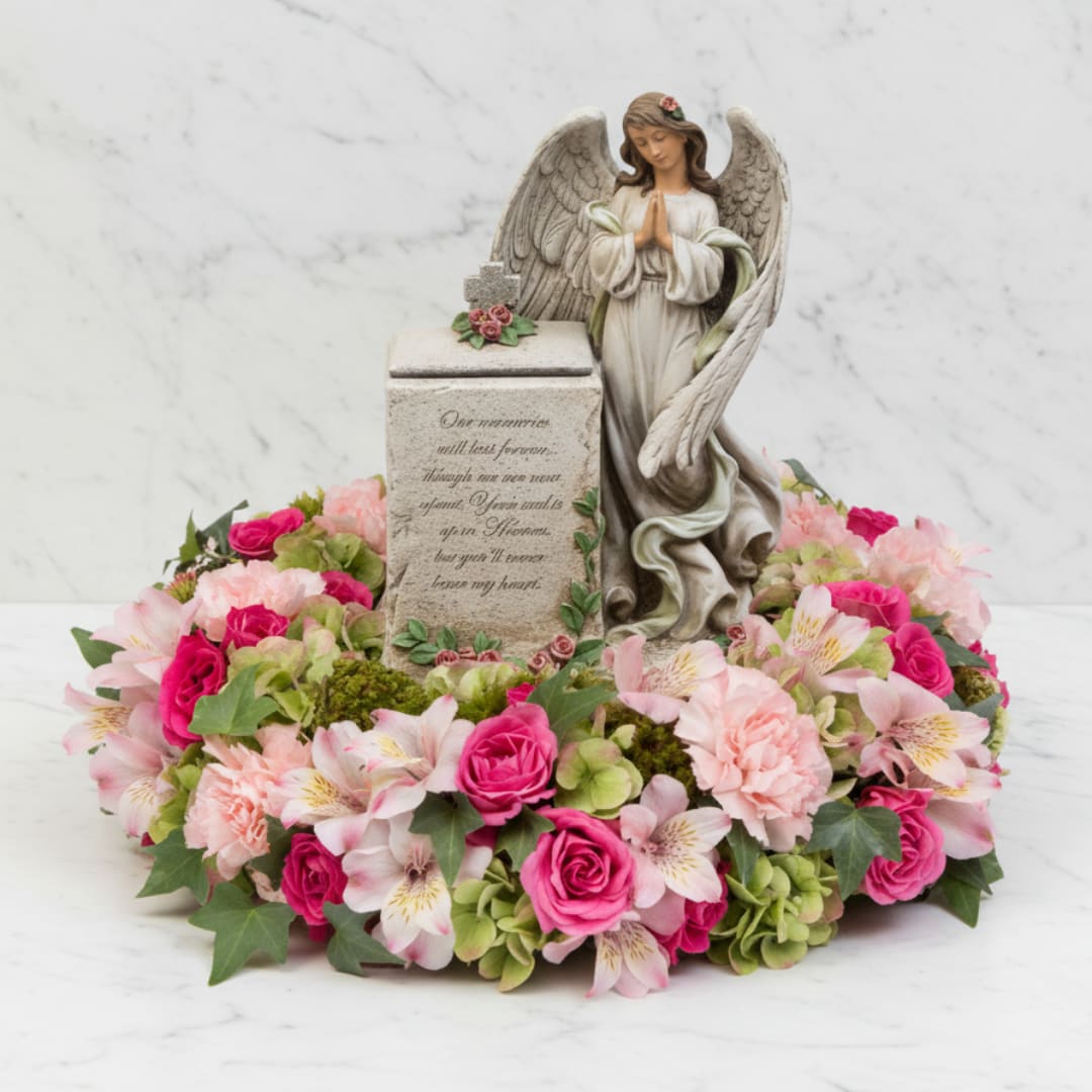 Angel figurine surrounded by pink flowers in a memorial wreath