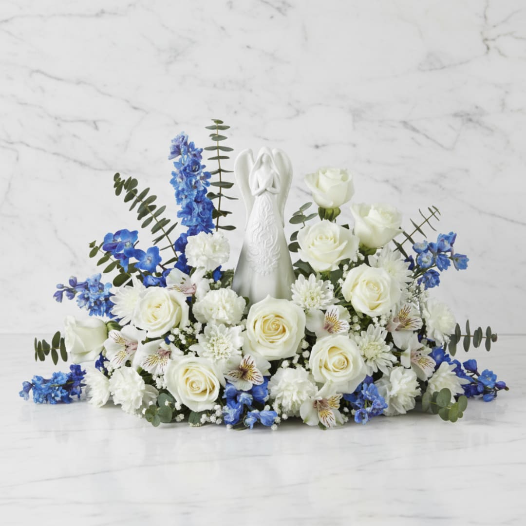 White rose and blue flower arrangement with an angel figurine centerpiece