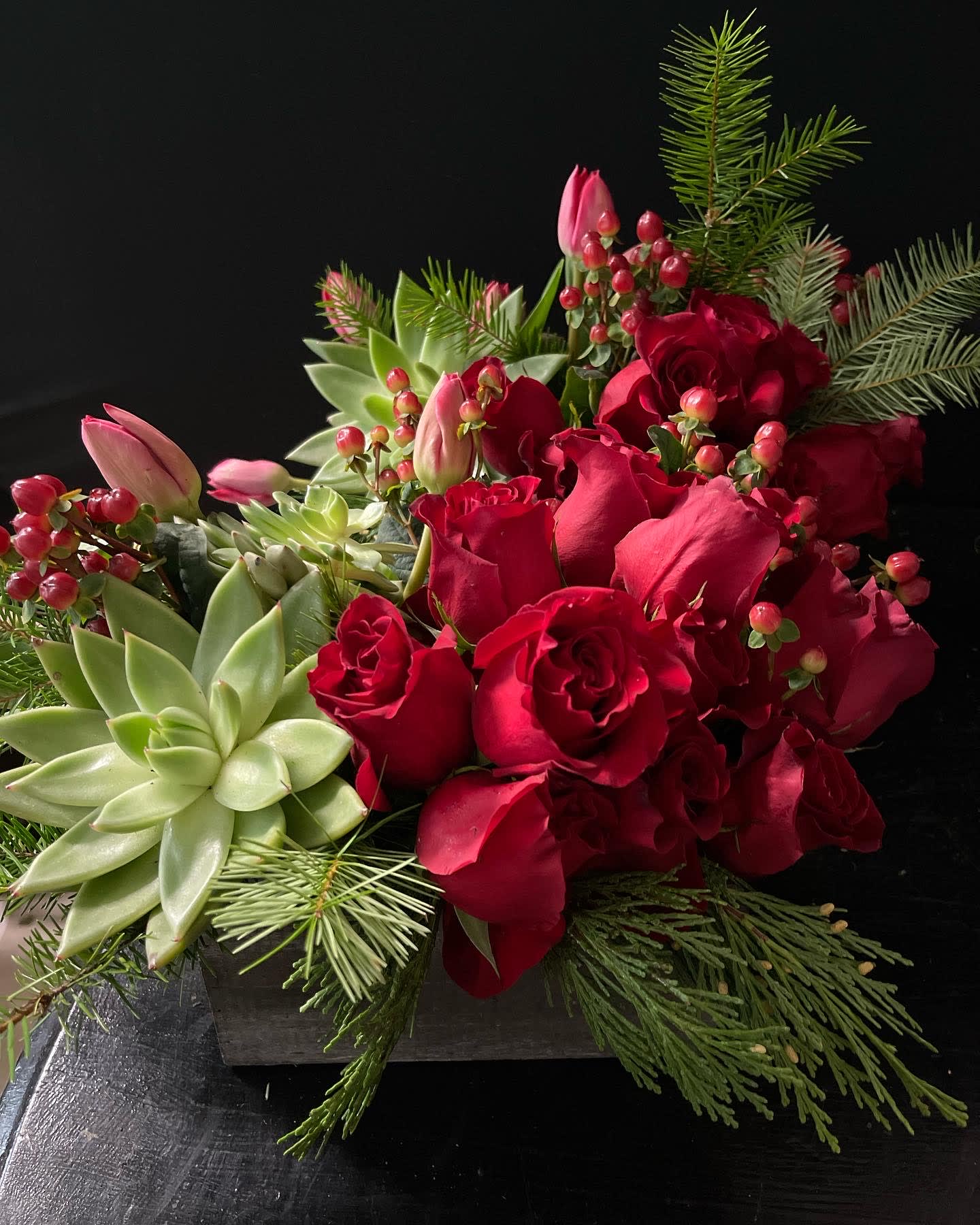 Red roses and pink tulips arranged with succulents in a low container