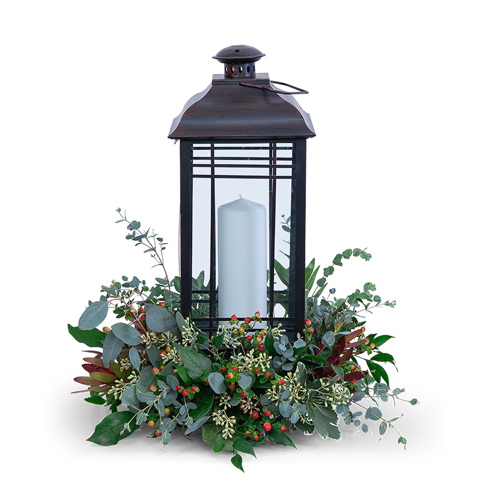 Black lantern with a white candle and greenery base