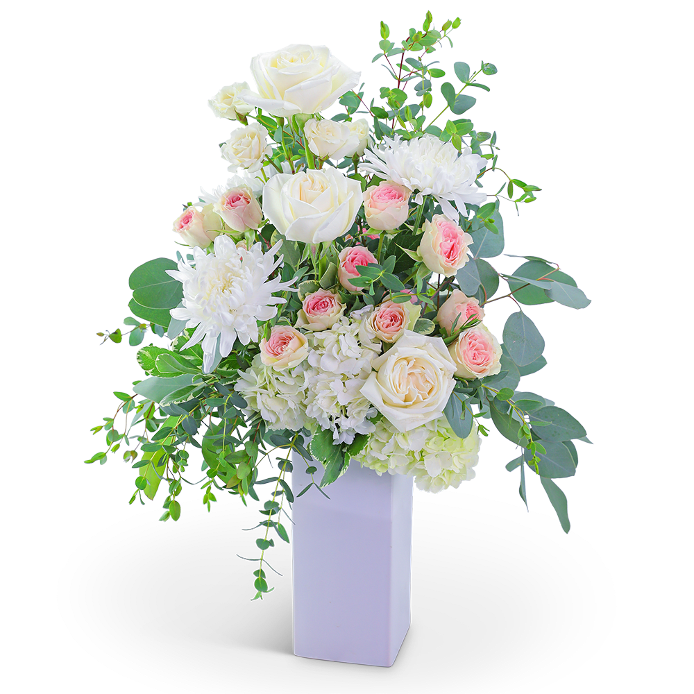 White roses and pink spray roses in a tall white vase