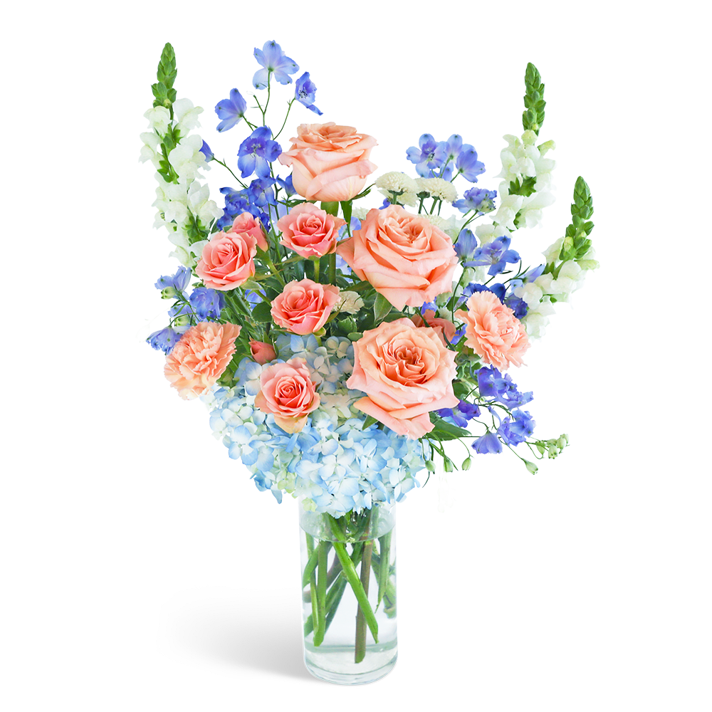 Peach roses and blue flowers in a clear glass vase